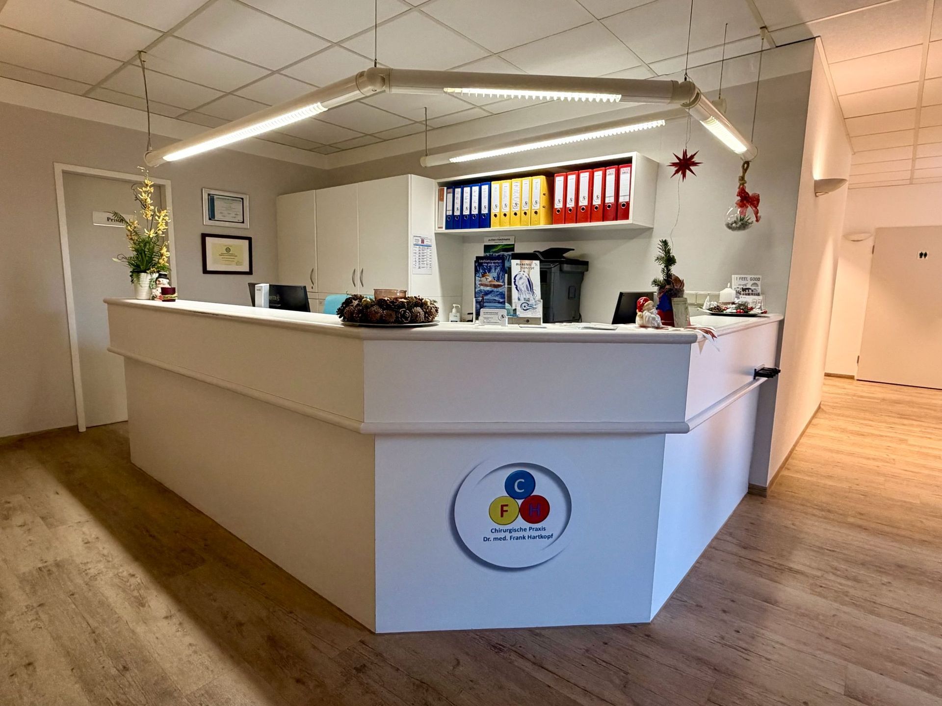 Empfangstresen mit Logo, farbenfrohen Ordnern und dekorativer Beleuchtung.