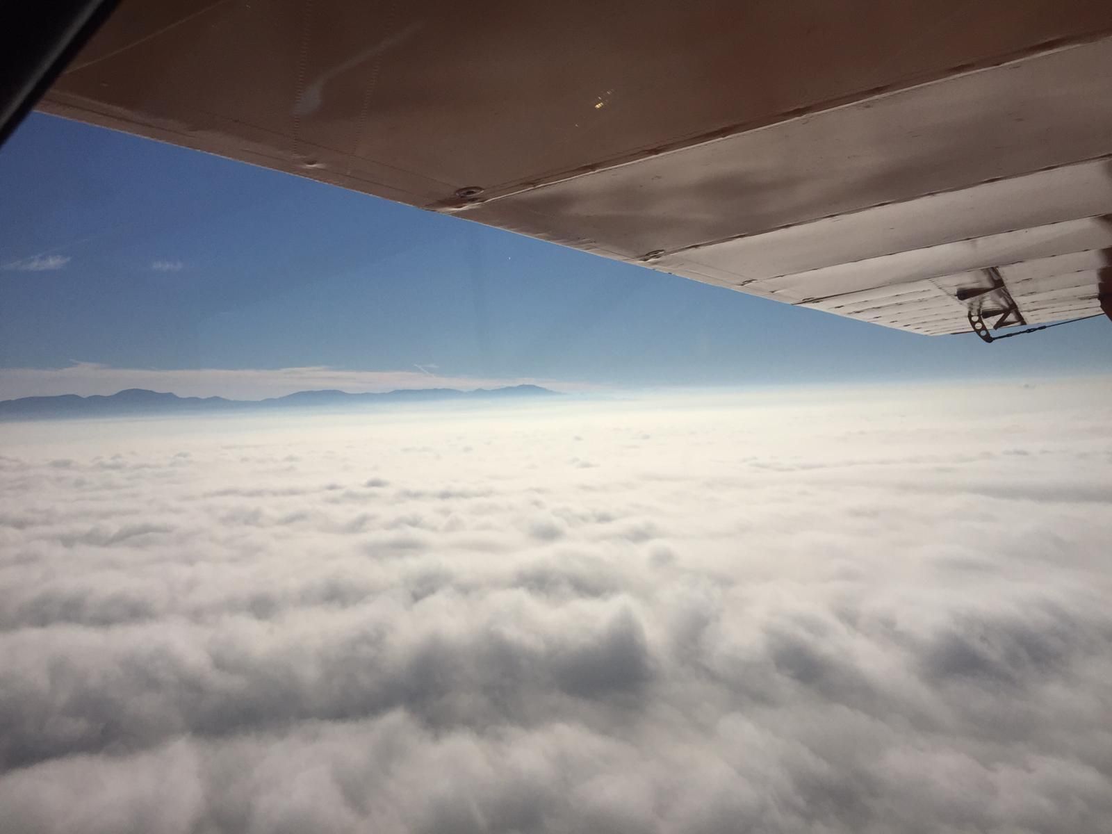 Tragfläche eines Flugzeugs über einer geschlossenen Wolkendecke