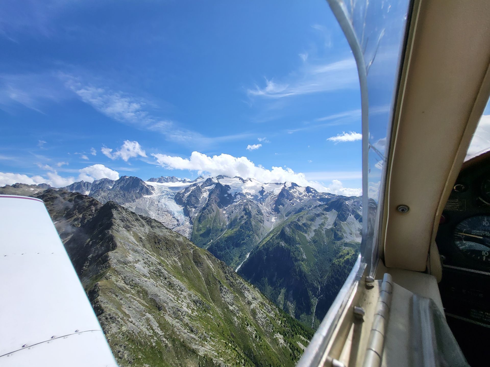 Blick entlang der Tragfläche auf schneebedeckte Alpengipfel