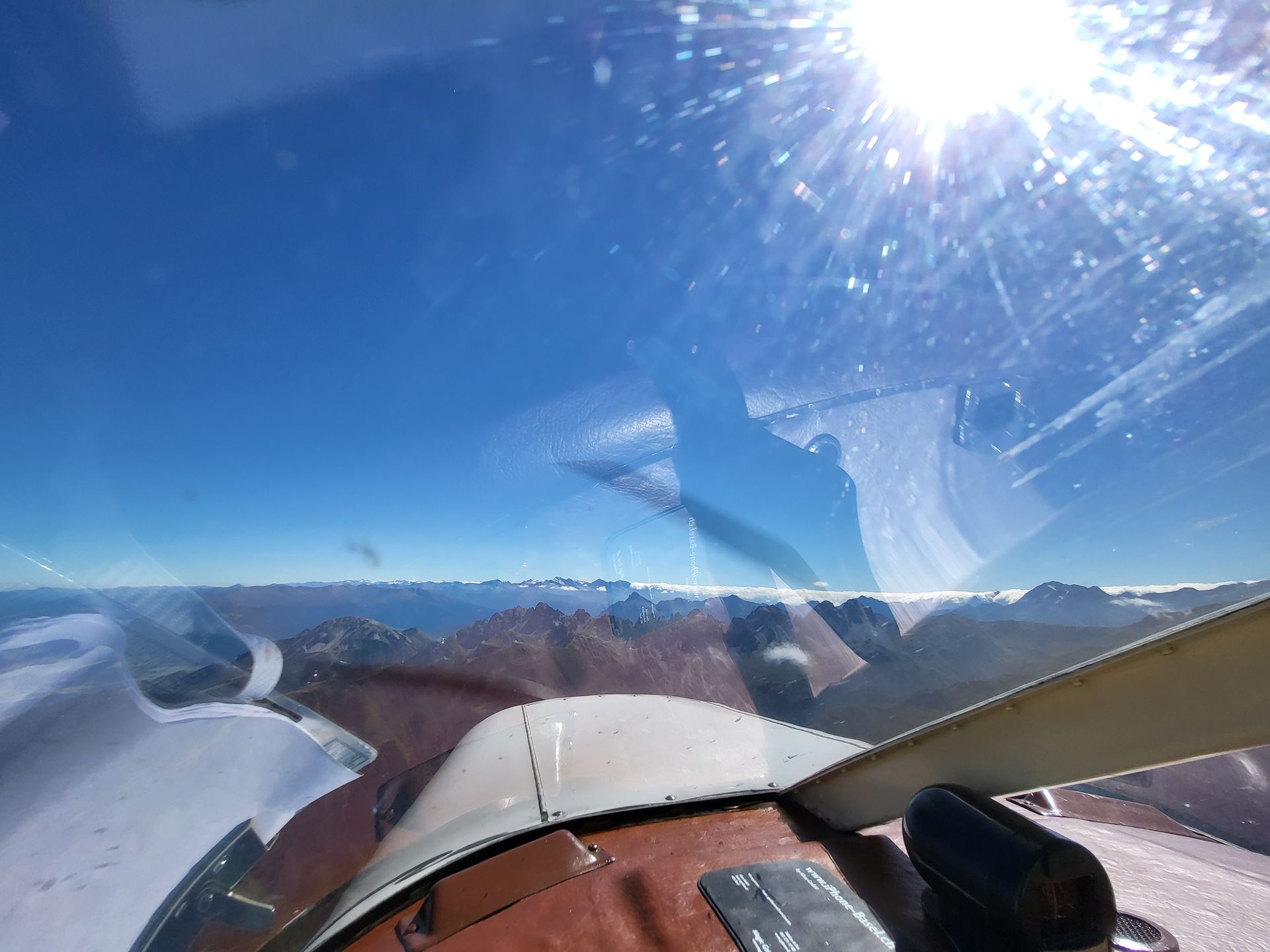Blick durch die Cockpitscheibe auf eine alpine Berglandschaft