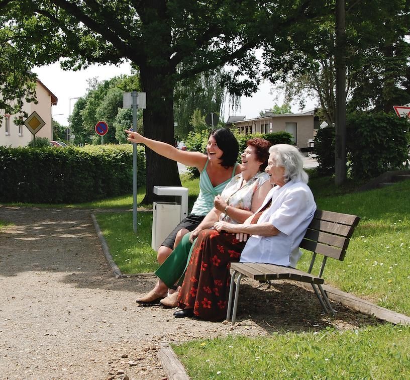 Mitarbeiterin mit Kunden auf einer Parkbank sitzend