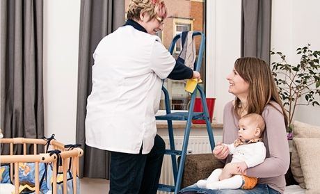 Mitarbeiterin putzt Fenster für eine junge Familie