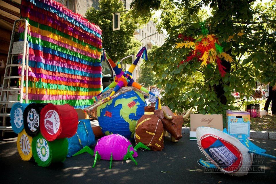 Bunte Piñatas, darunter eine Erdkugel, in festlicher Freiluftkulisse.