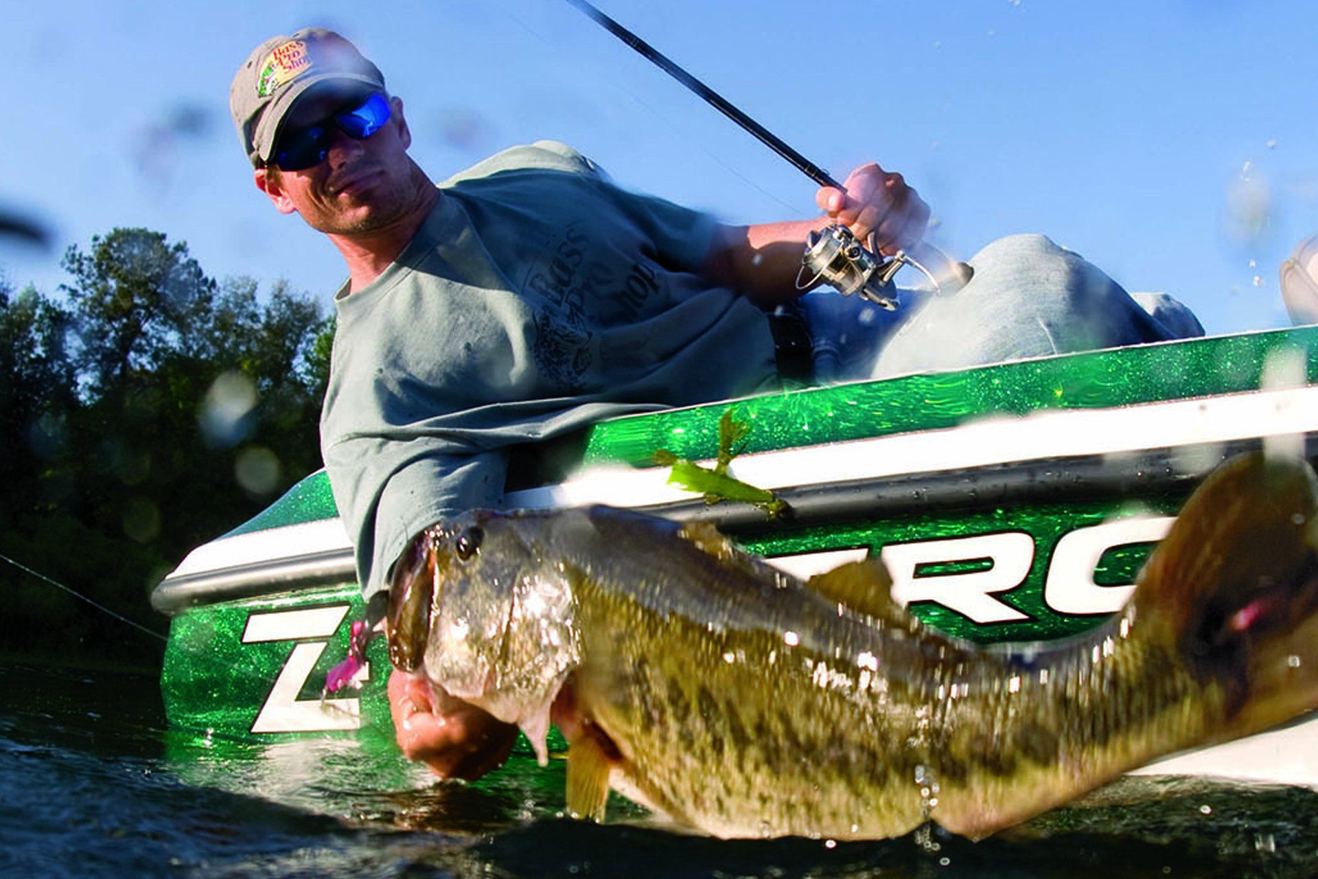Photo of a man in a boat lifting a green fish out of the water.