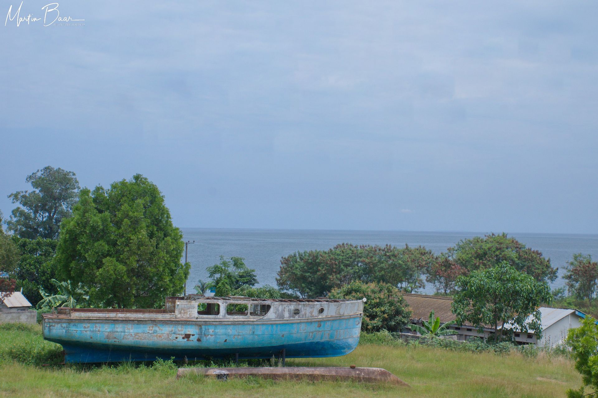 Blick von Entebbe in Uganda auf den Viktoriasee. Trocken gelegtes Schiff vor dem See.