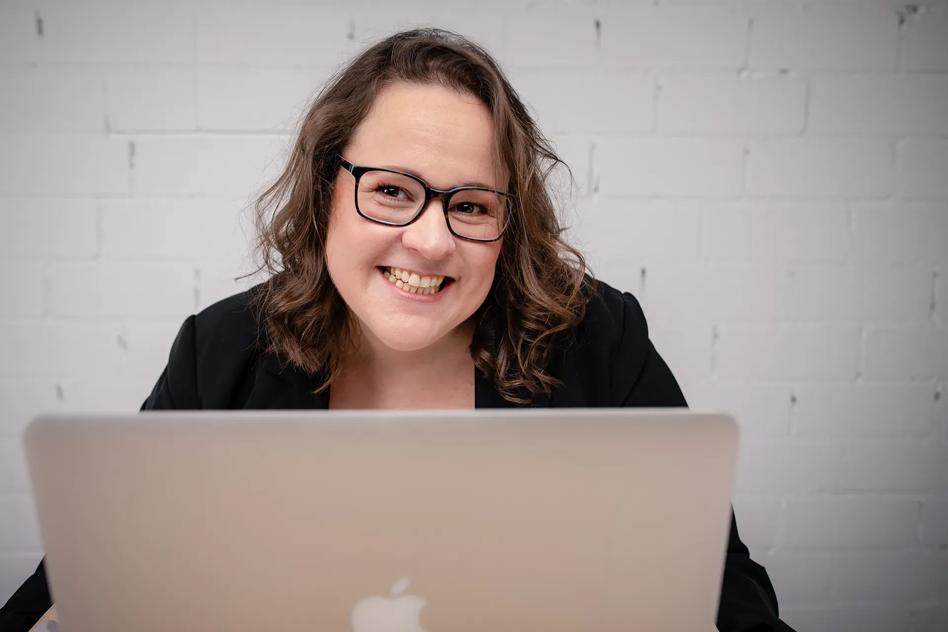 Katja Hero sitzt am MacBook und lächelt in die Kamera