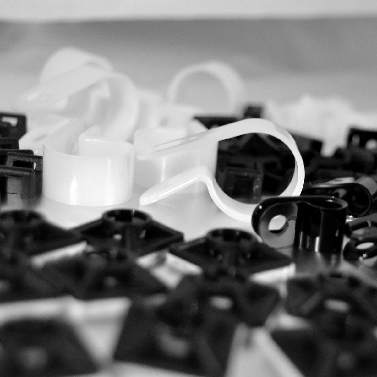 Befestigungstechnik von Pro-Parts: Weiße P-Clipse, schwarze Kabelschellen sowie schwarze Klebesockel