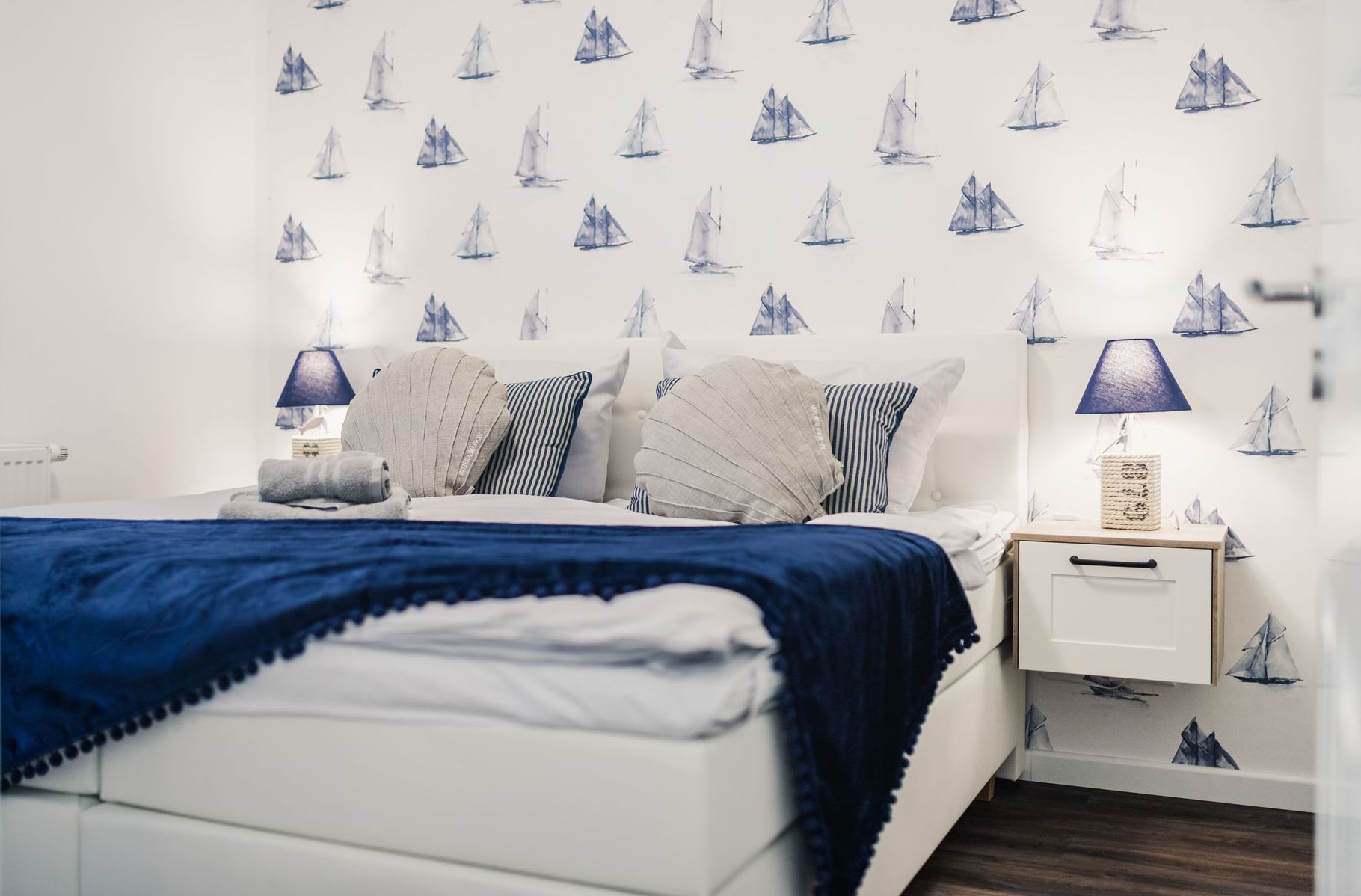 Boxspring-Doppelbett vor moderner Tapete mit Segelbooten