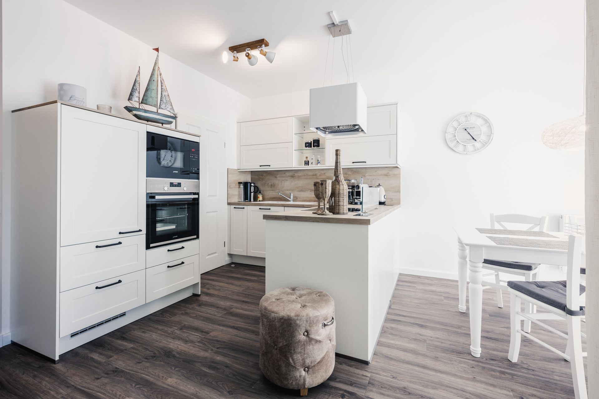 Weisse Küche mit Backofen, Kochtresen, Tisch, Stühle