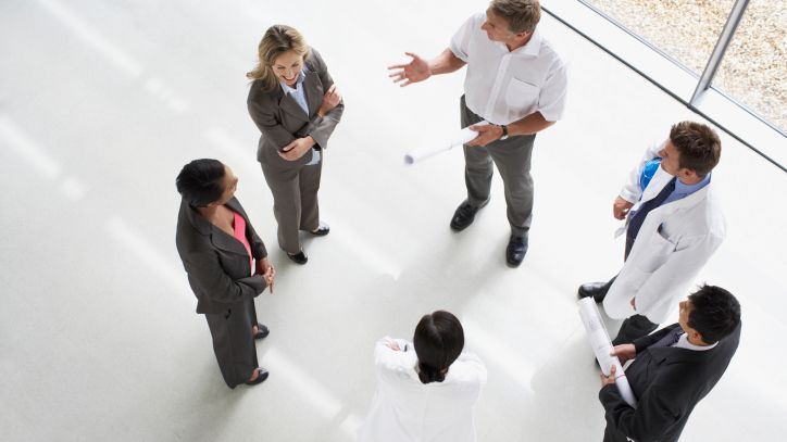 Eine Gruppe von Fachleuten in Geschäftskleidung traf sich zu einer Diskussion in einem hellen Raum.