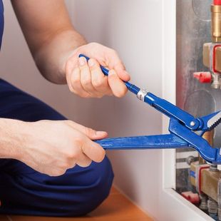general contractor repairs plumbing with blue pliers
