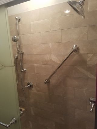 tiled shower stall for senior bathroom remodel with shower grab bars and dual shower heads