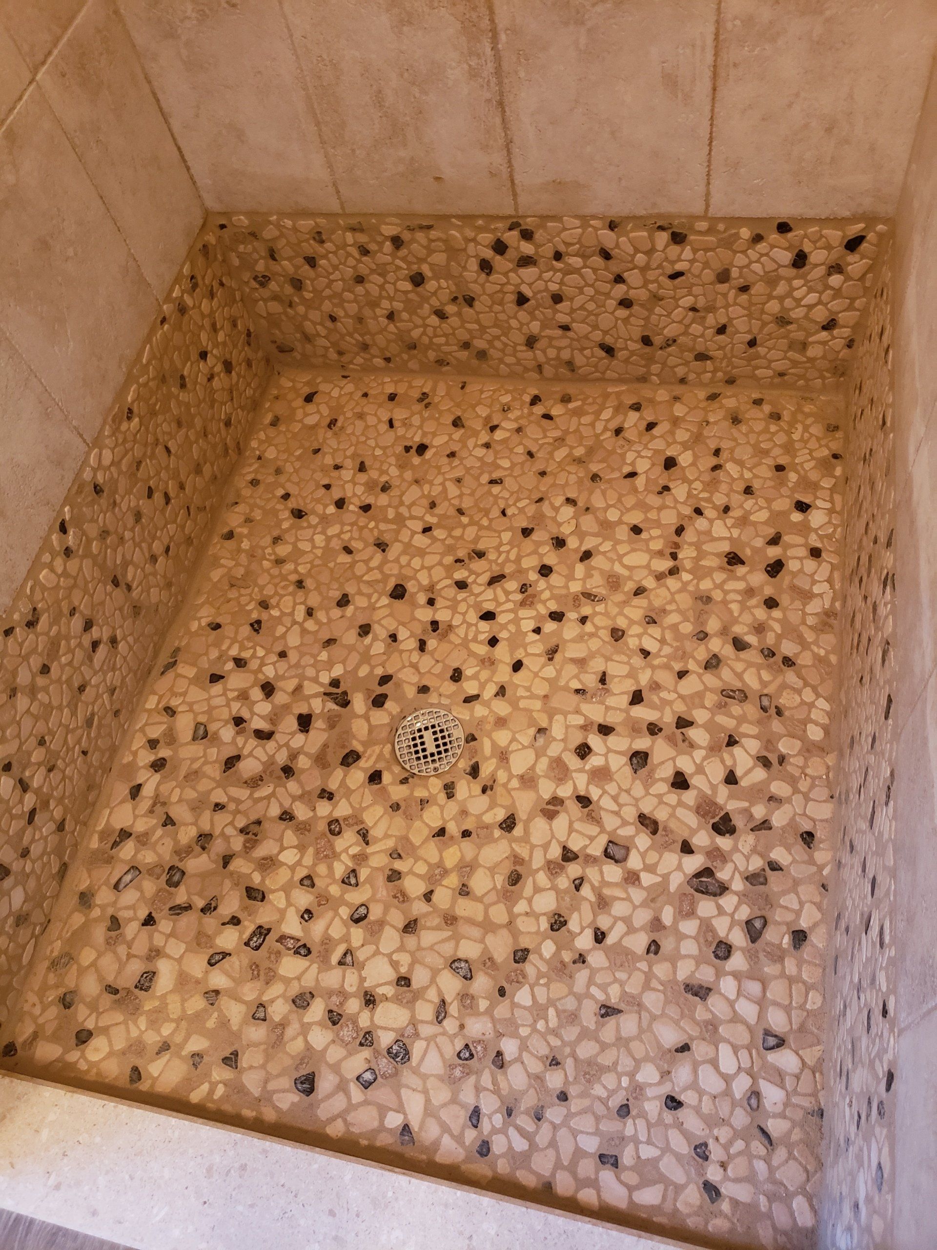 Close up of organic shape and earth tone pebble shower floor in Glenside bathroom remodel