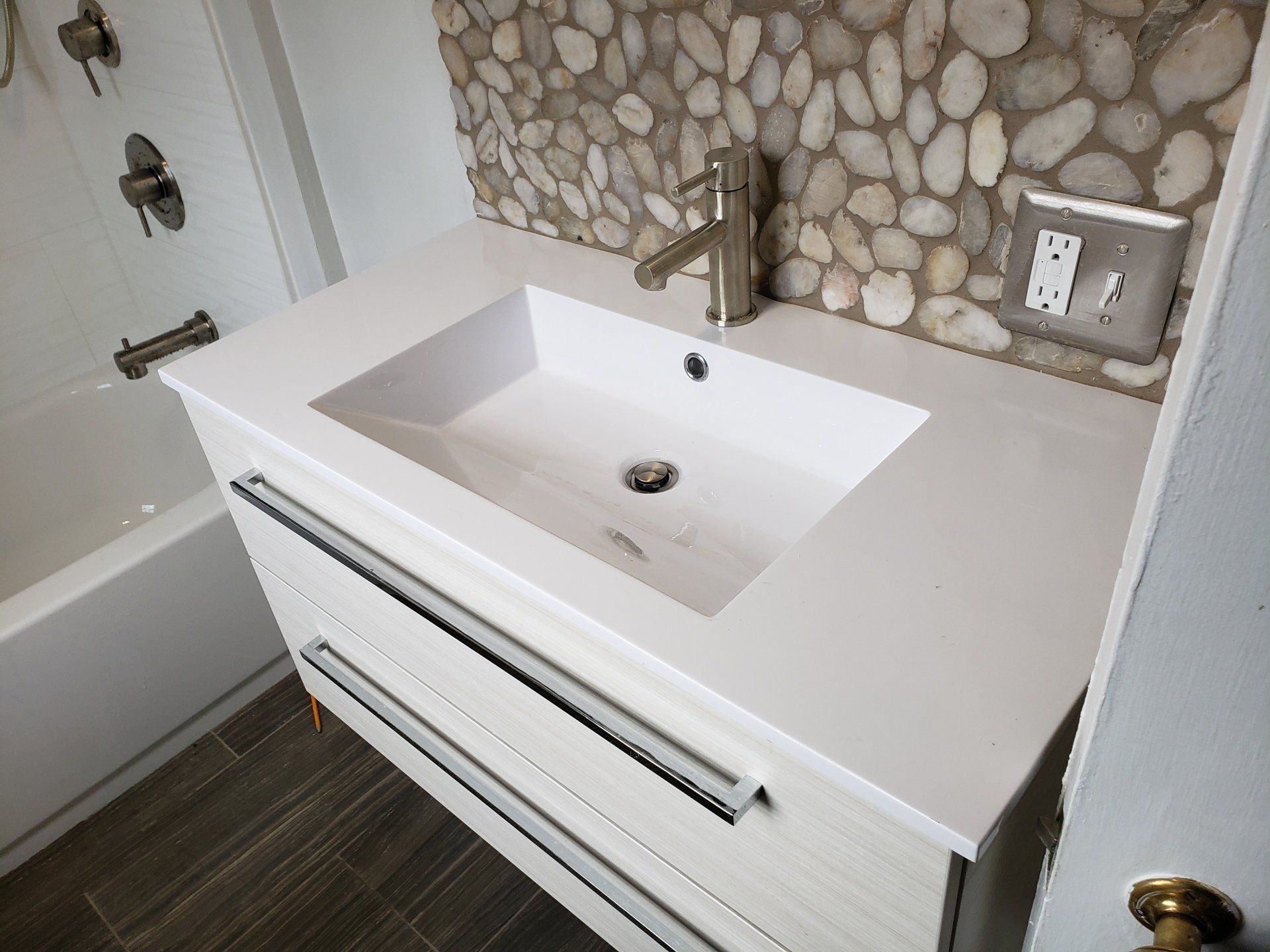 Close up of modern style floating vanity, sink, and custom designed and installed stone backsplash in Willow Grove master bathroom remodel..