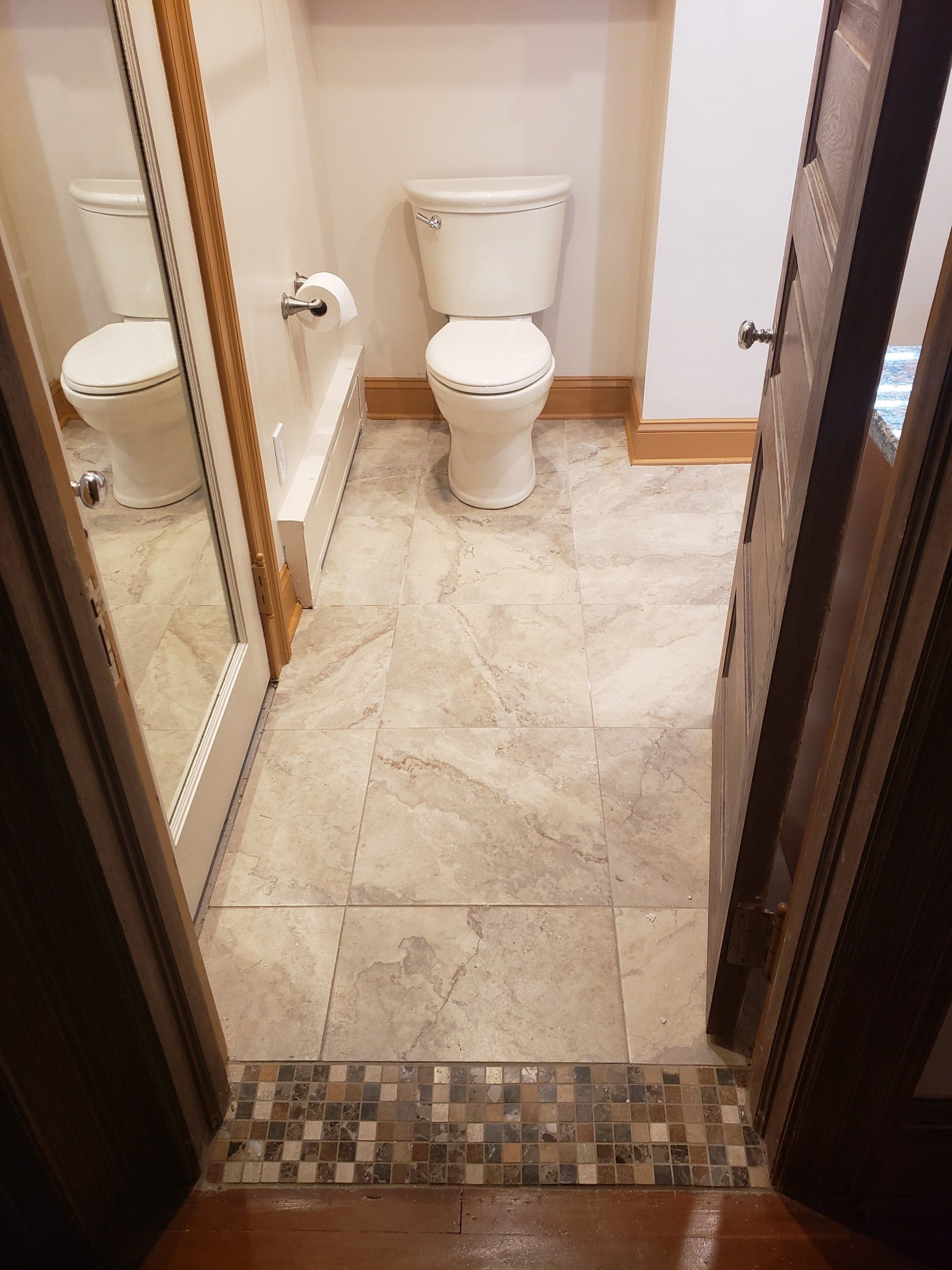Close up view of mosaic tile used in trim and repeated as a transition strip between the bathroom and hallway floors in Cheltenham bathroom remodel.
