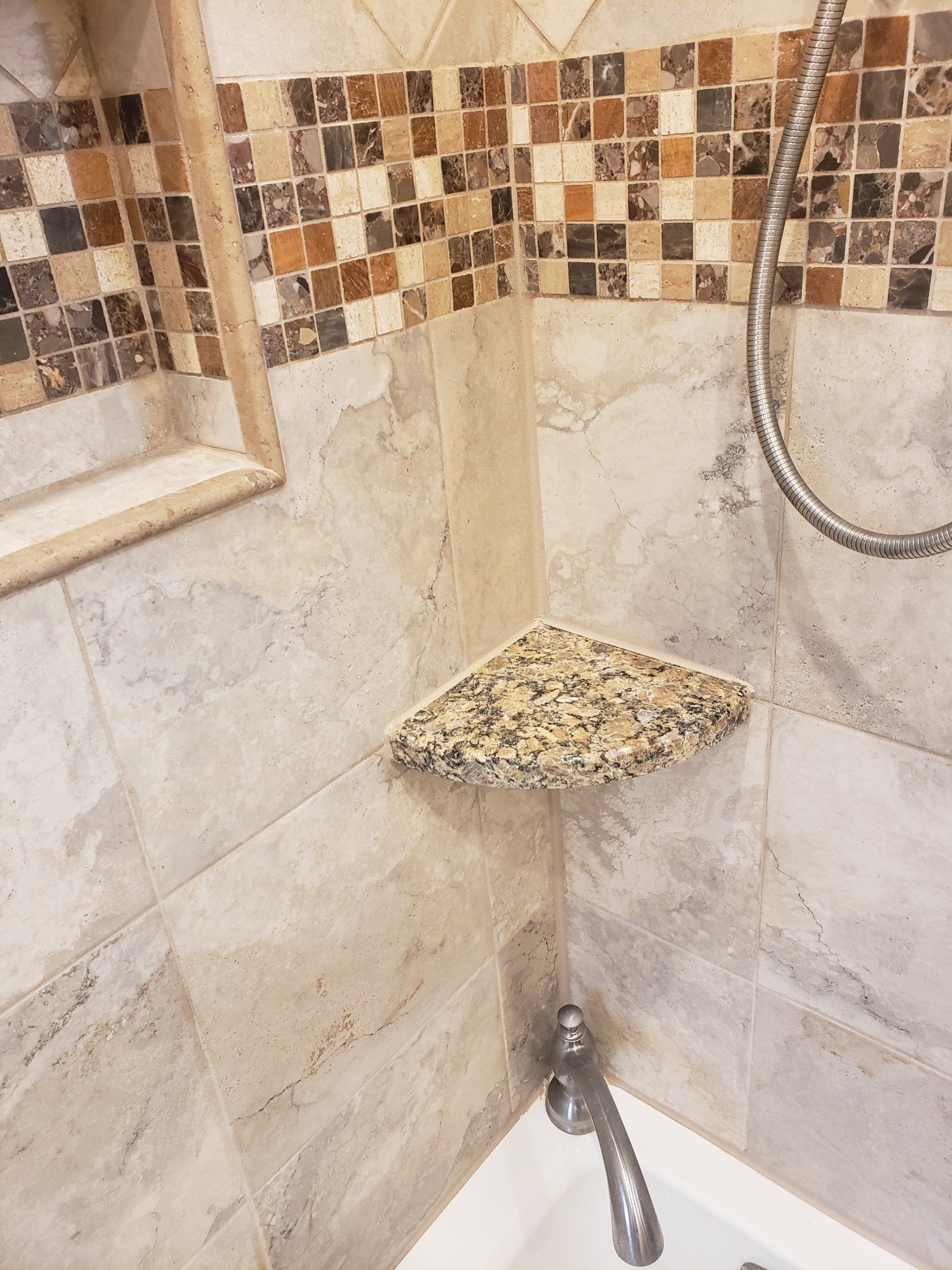 Close up view of shower corner shelf, shower wall tiles and mosaic tile trim design in Cheltenham bathroom remodel.