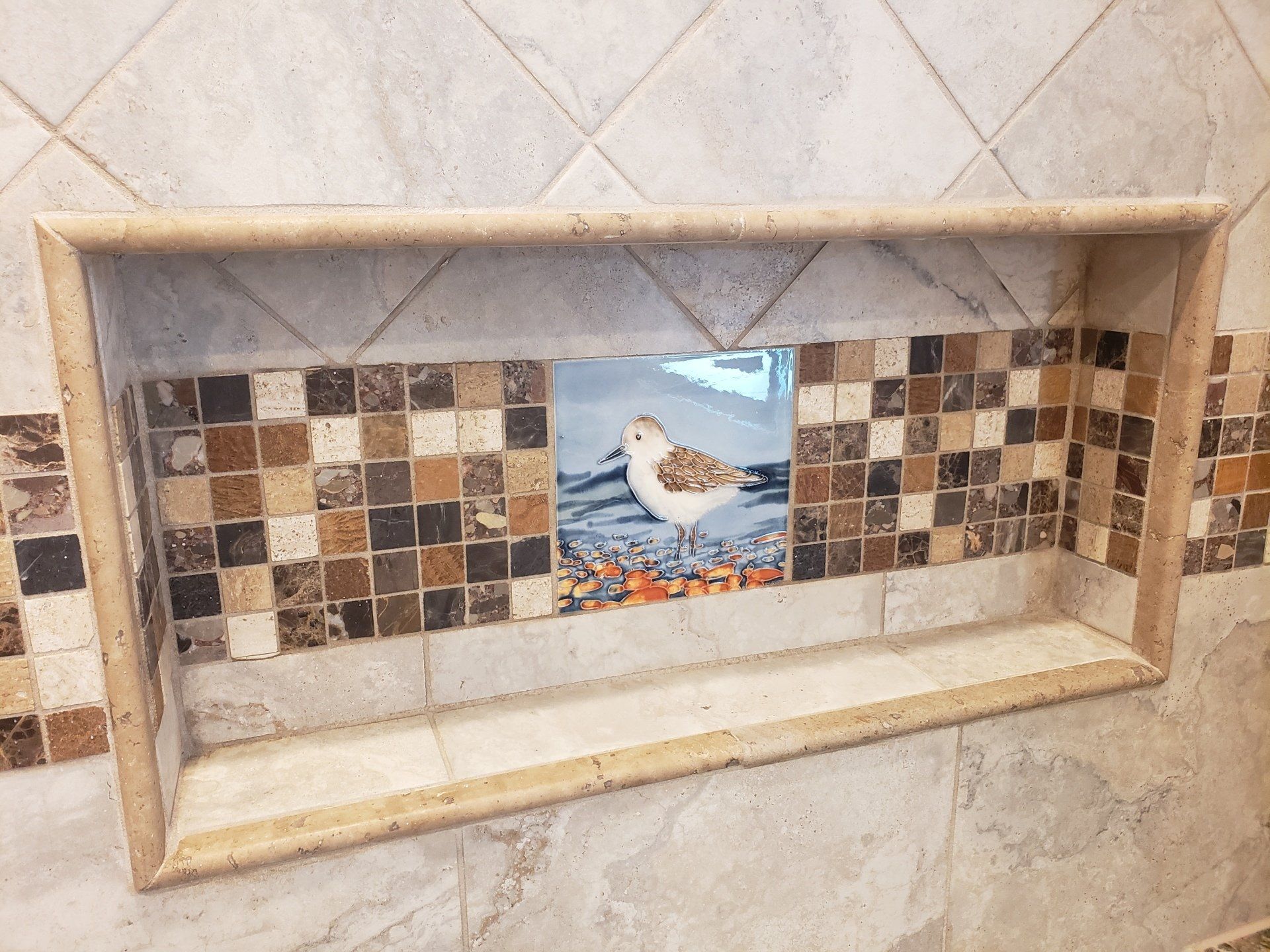 Pocket shelf in shower with mosaic trim tile and focal point of a painted tile adds lovely character in this Cheltenham bathroom remodel.