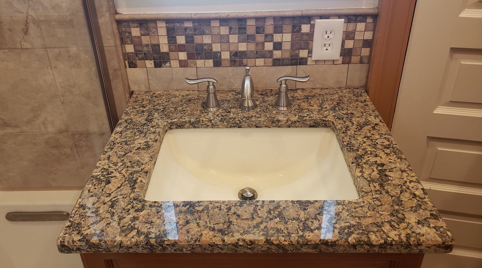 Sink with granite countertop and mosaic tile backsplash in Cheltenham bathroom remodel.
