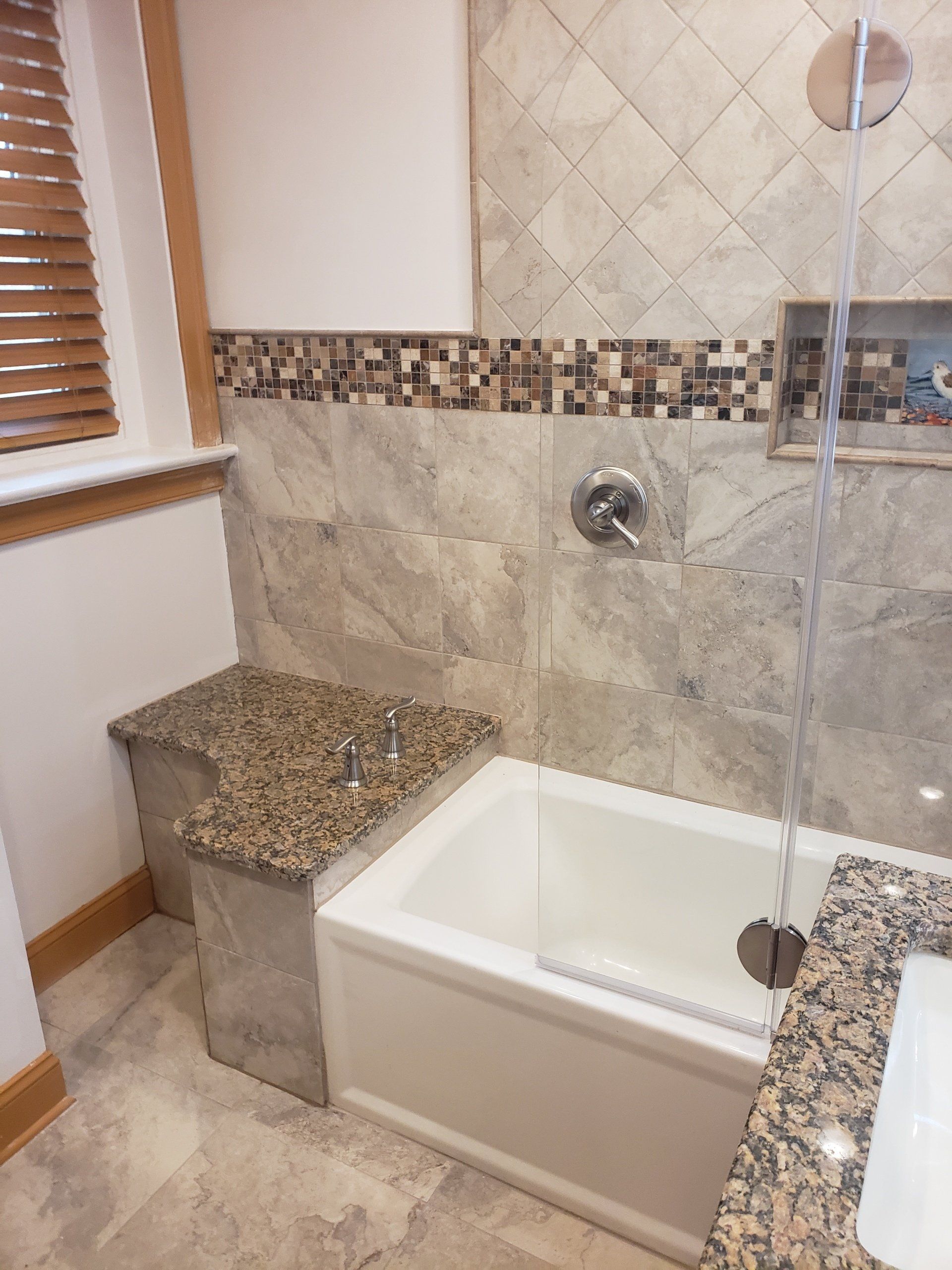 View of custom built bench with custom granite top as repurposed space between the shower tub and wall in this Cheltenham bathroom remodel.