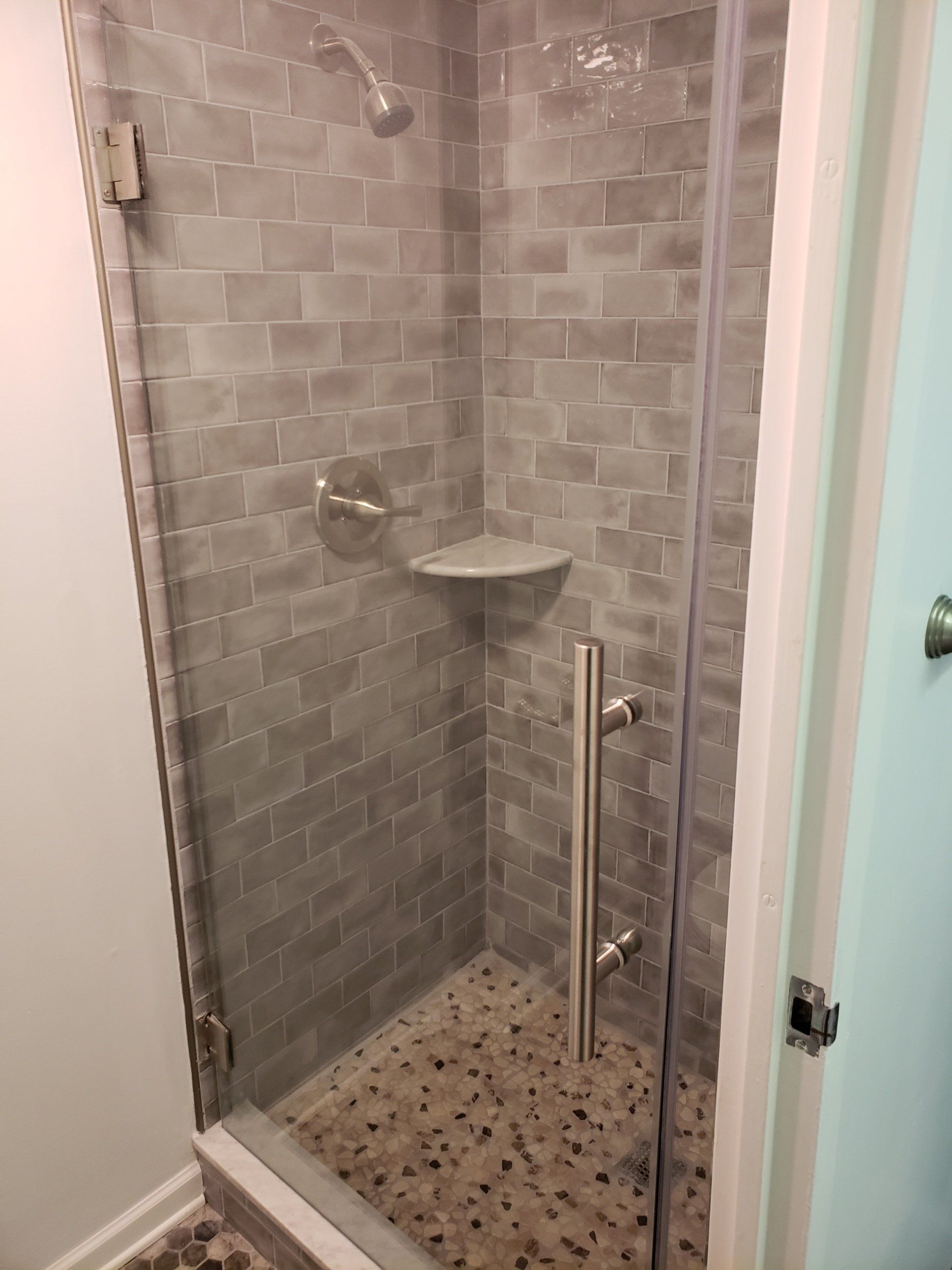 Jenkintown condo bathroom remodel close up of shower floor to ceiling subway tiles and shower door.
