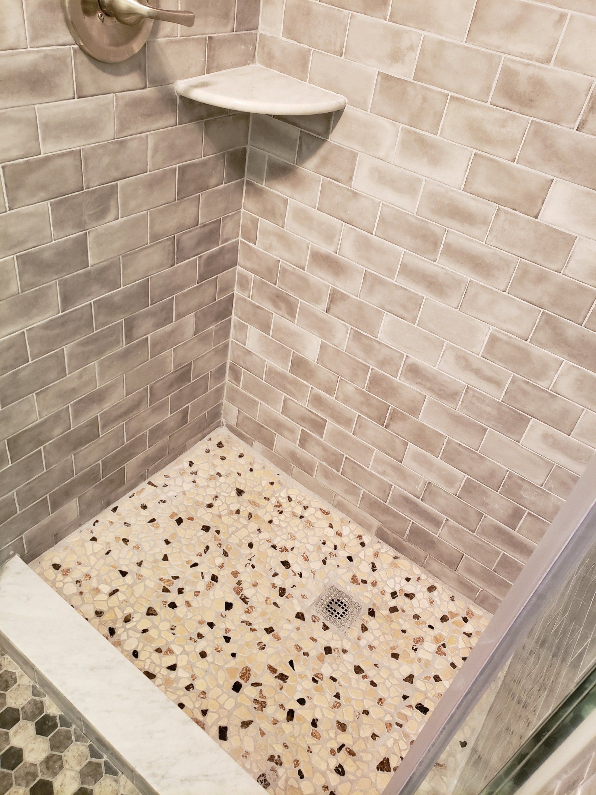 Jenkintown condo bathroom remodel close up of shower floor tiles and marble corner shelf.