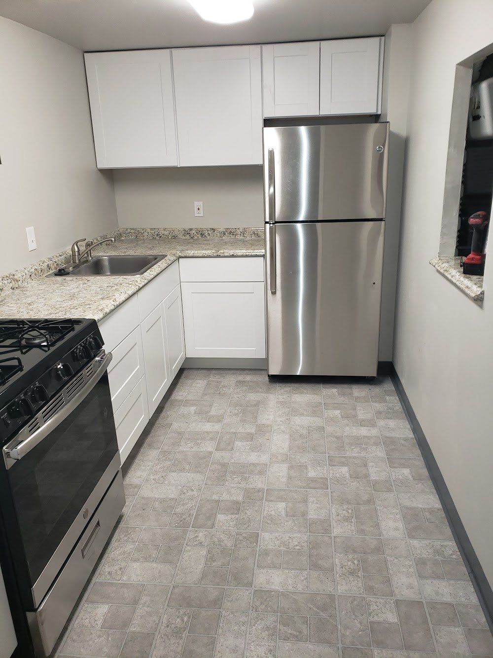 After photo of new tile flooring, appliances and countertop in compact kitchen remodel in a Jenkintown condominium