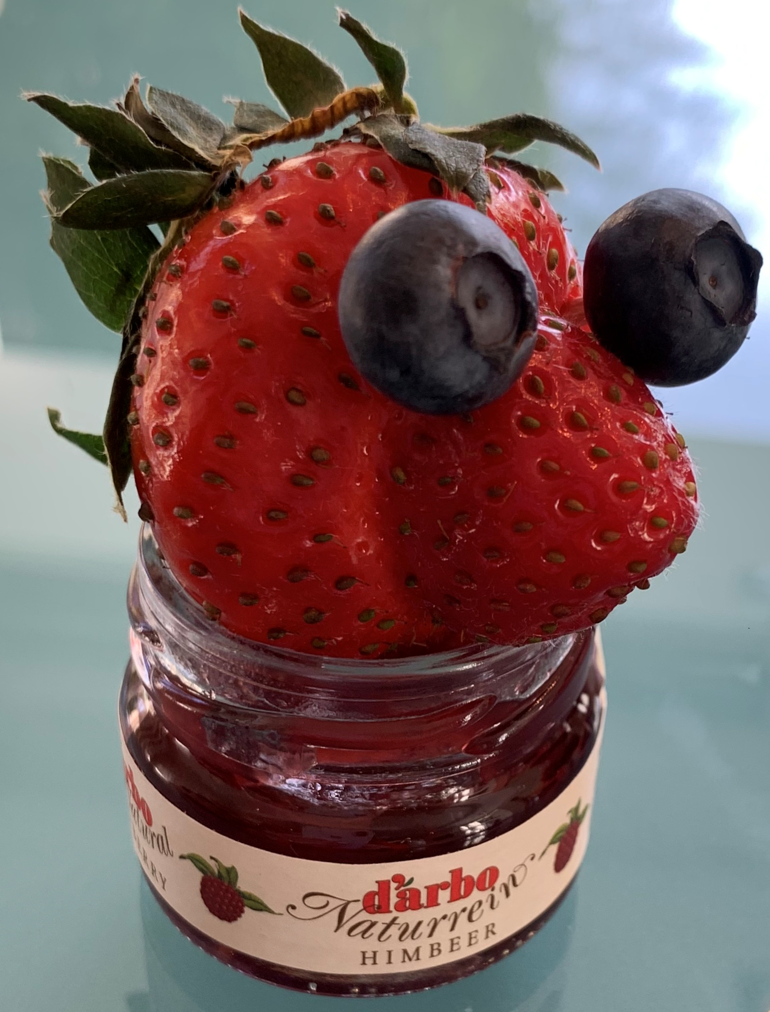 Eine Erdbeere mit Traubenaugen in einem Marmeladenglas