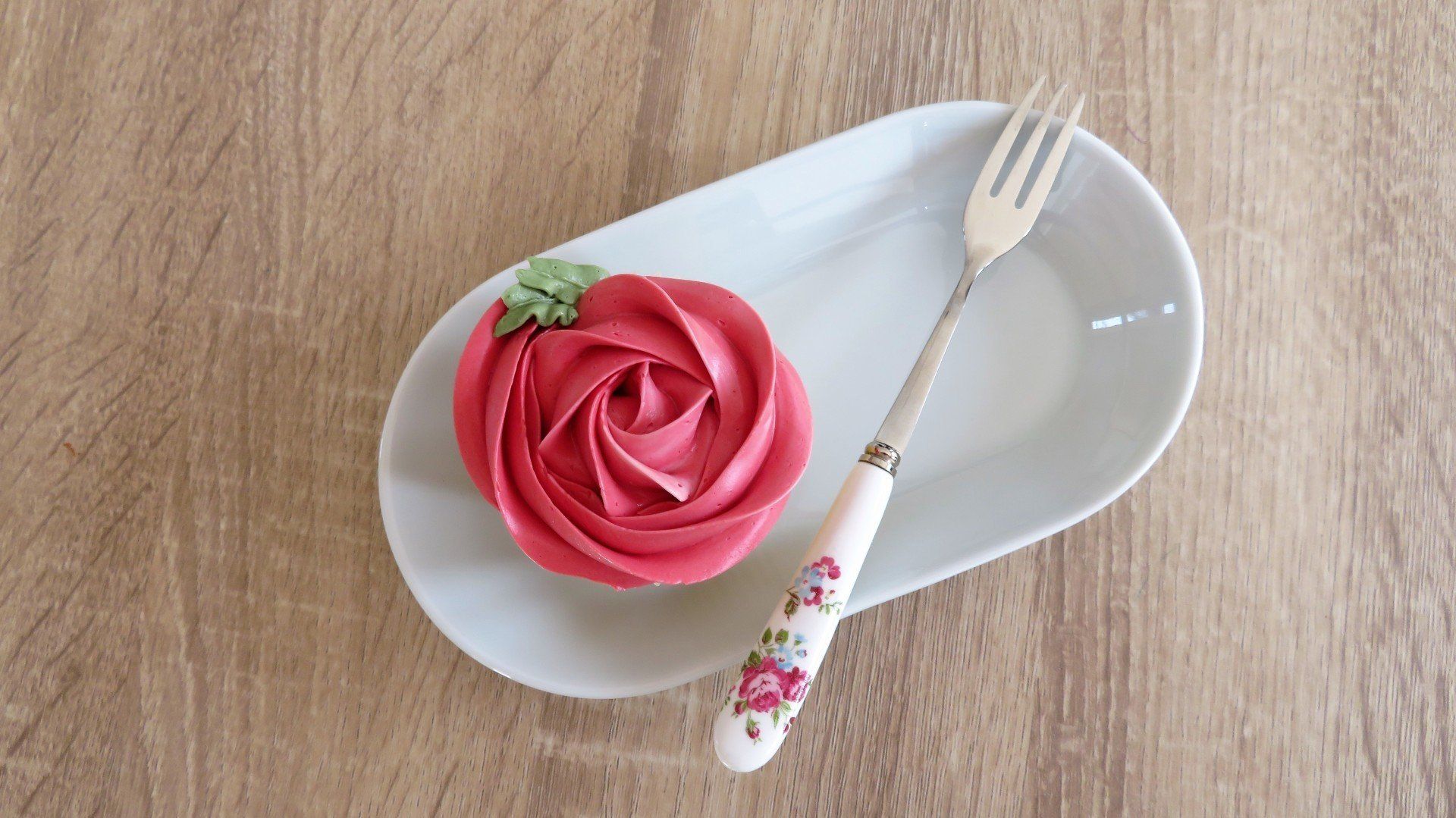 Pink swirl rose cupcake on plate with fork