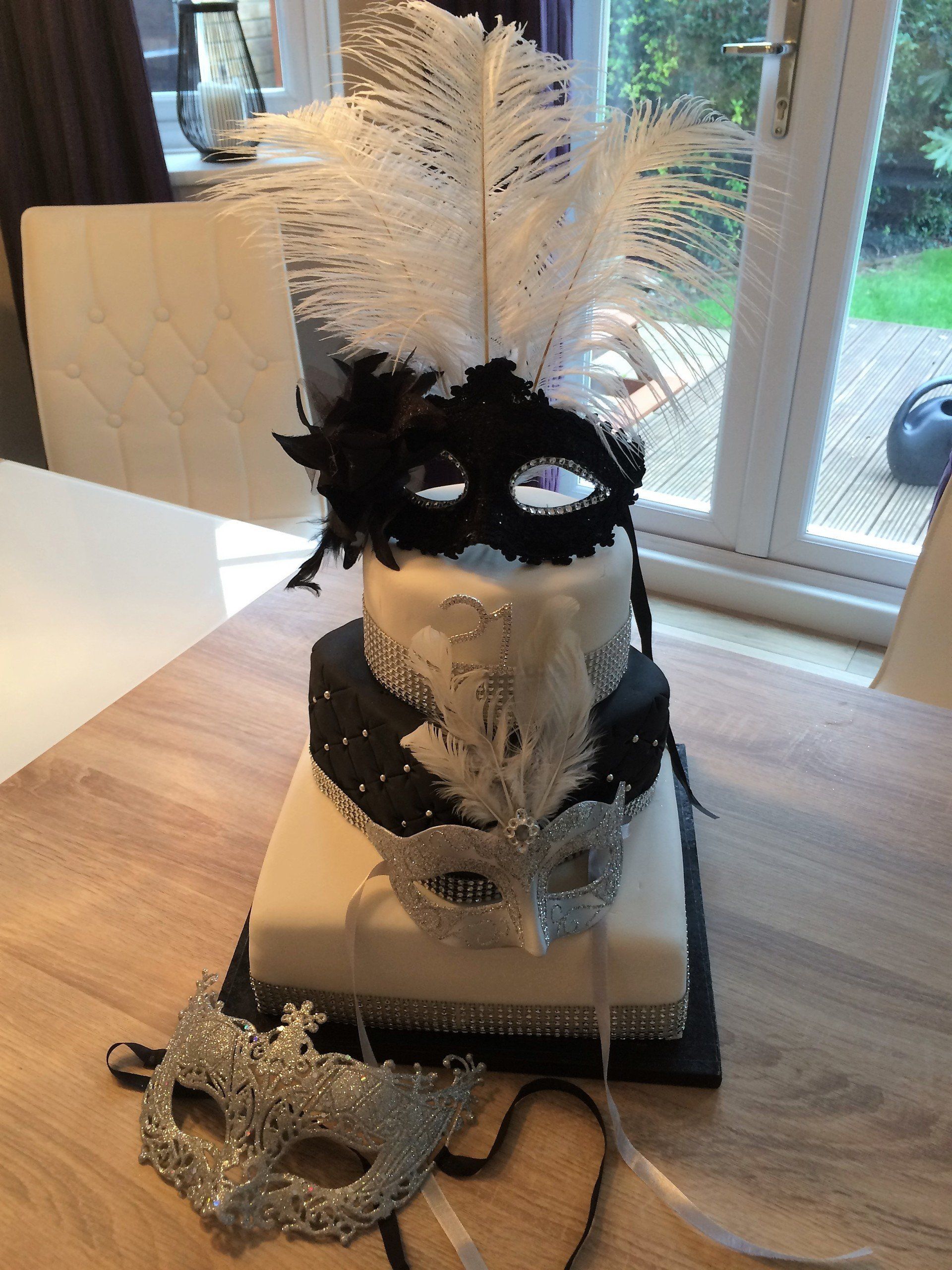 3 tier celebration cake with feathers and masquerade mask