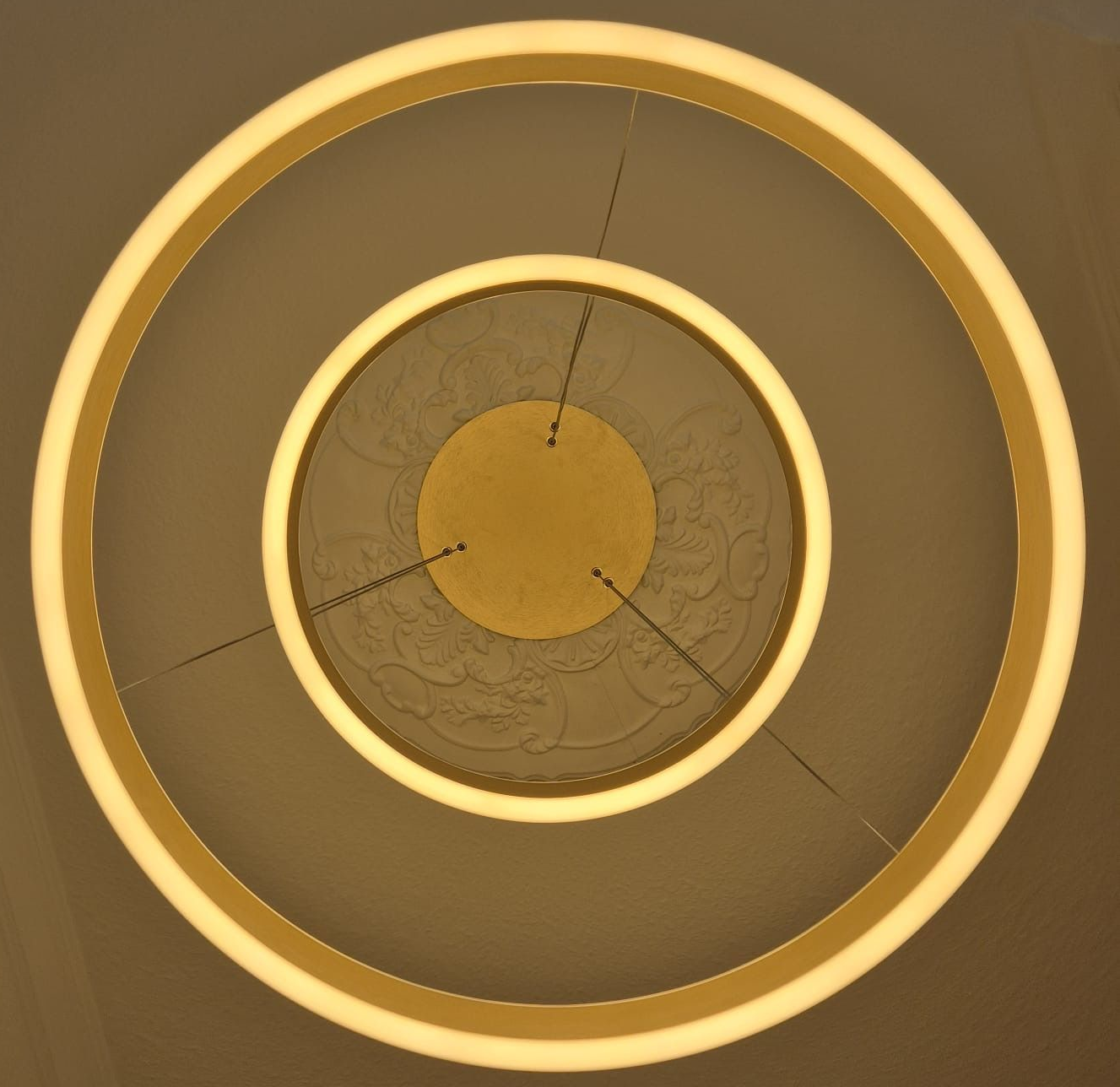 Runde goldene Lampe mit Stuck an weißer Decke.