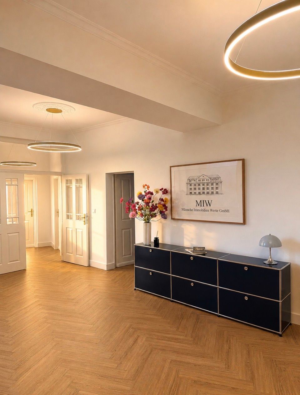 Eingangsbereich mit goldenen runden Lampen und einem blauen USM Haller Sideboard
