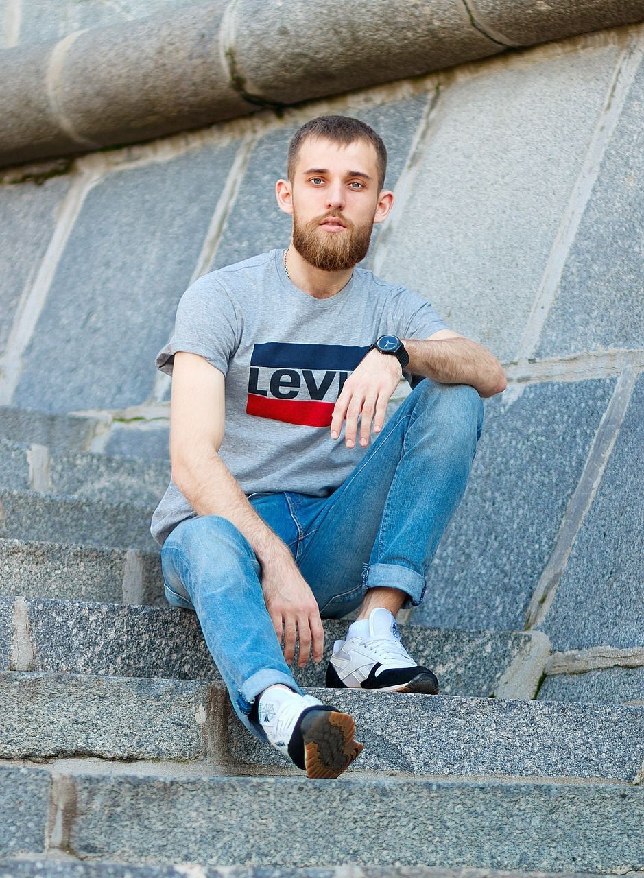 Mann sitzt nachdenklich auf Treppe und wirkt innerlich angespannt