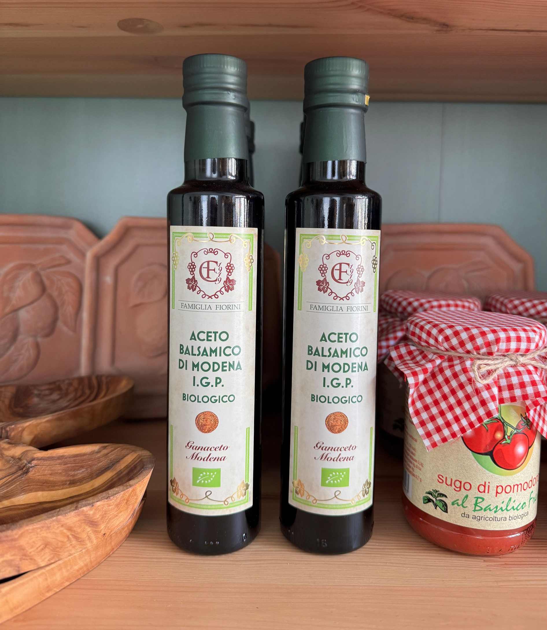 eine 0,25l und eine 0,5l Olivenöldose nebeneinander stehend umgeben von Steinen, Treibholz, Erde und Pflanzen