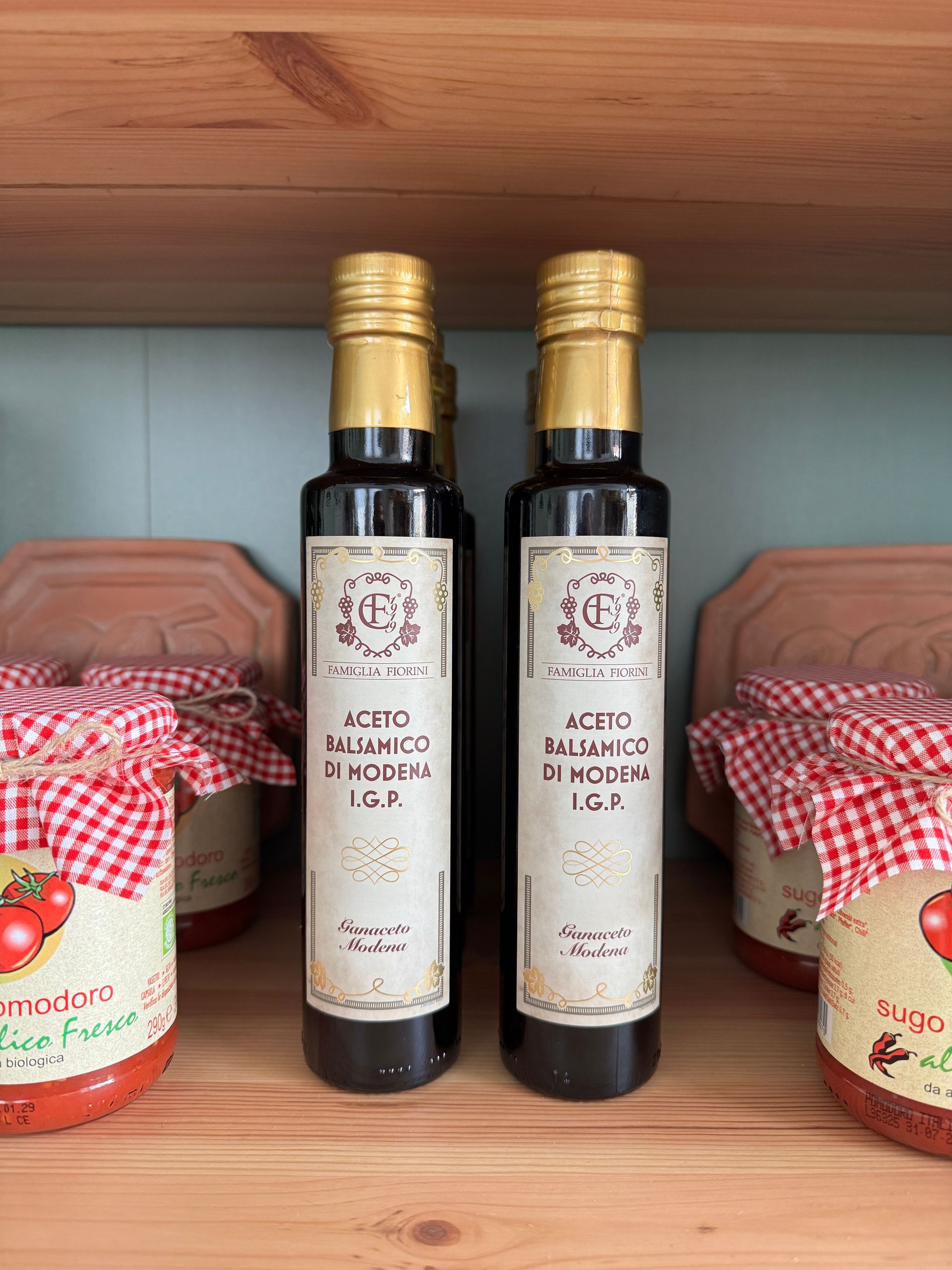 eine 0,25l und eine 0,5l Olivenöldose nebeneinander stehend umgeben von Steinen, Treibholz, Erde und Pflanzen