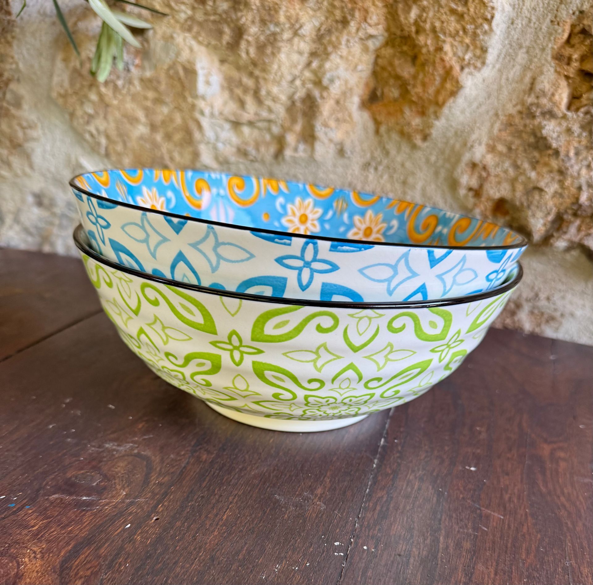 zwei große Keramikschalen mit einmal blauer und einmal grüner Muterung außen aufeinander gestapelt vor einer Steinrückwand