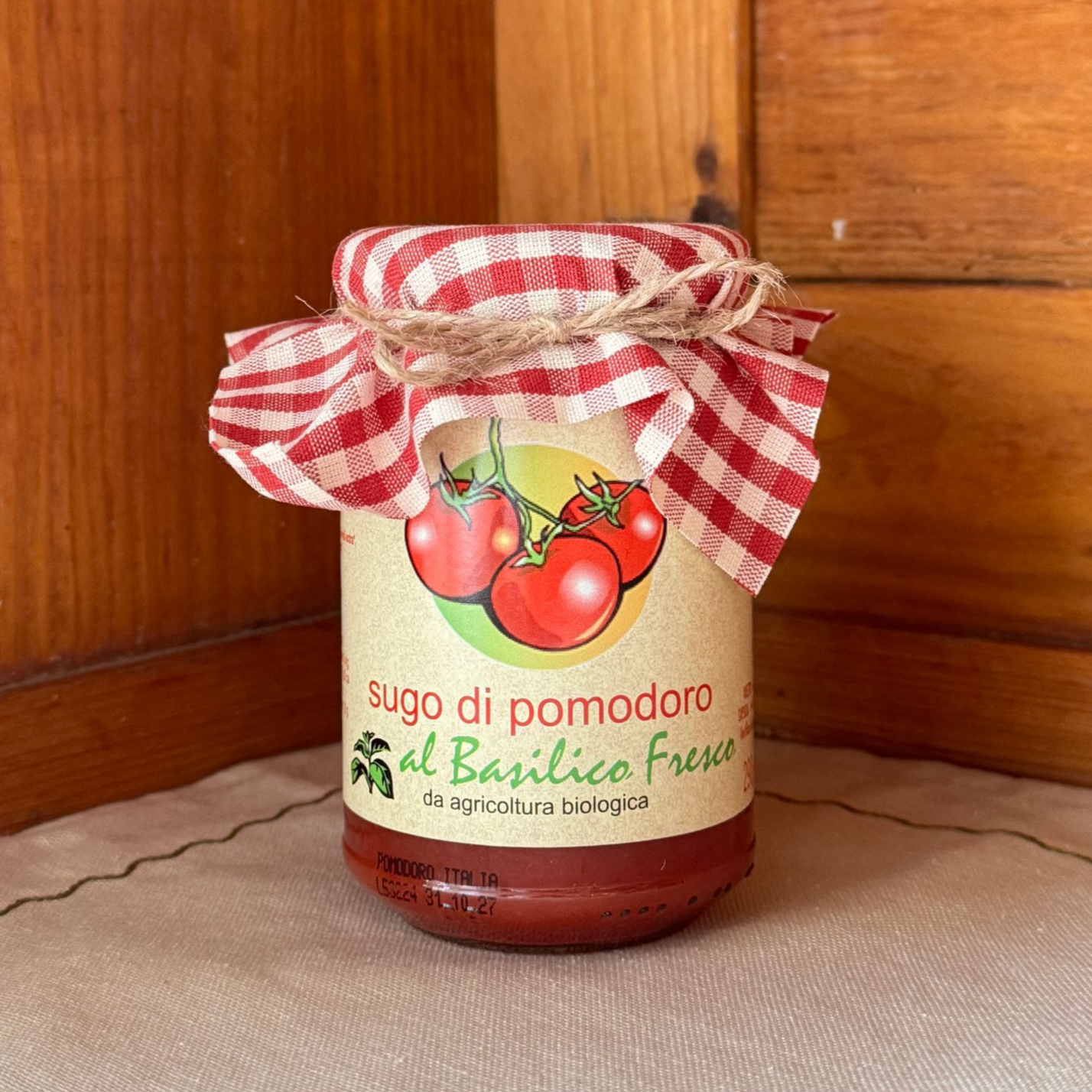 Einwegglas gefüllt mit Sugo di Pomodoro al Basilico Fresco und mit einem durch Schnur am Deckel festgebundenem Stoff