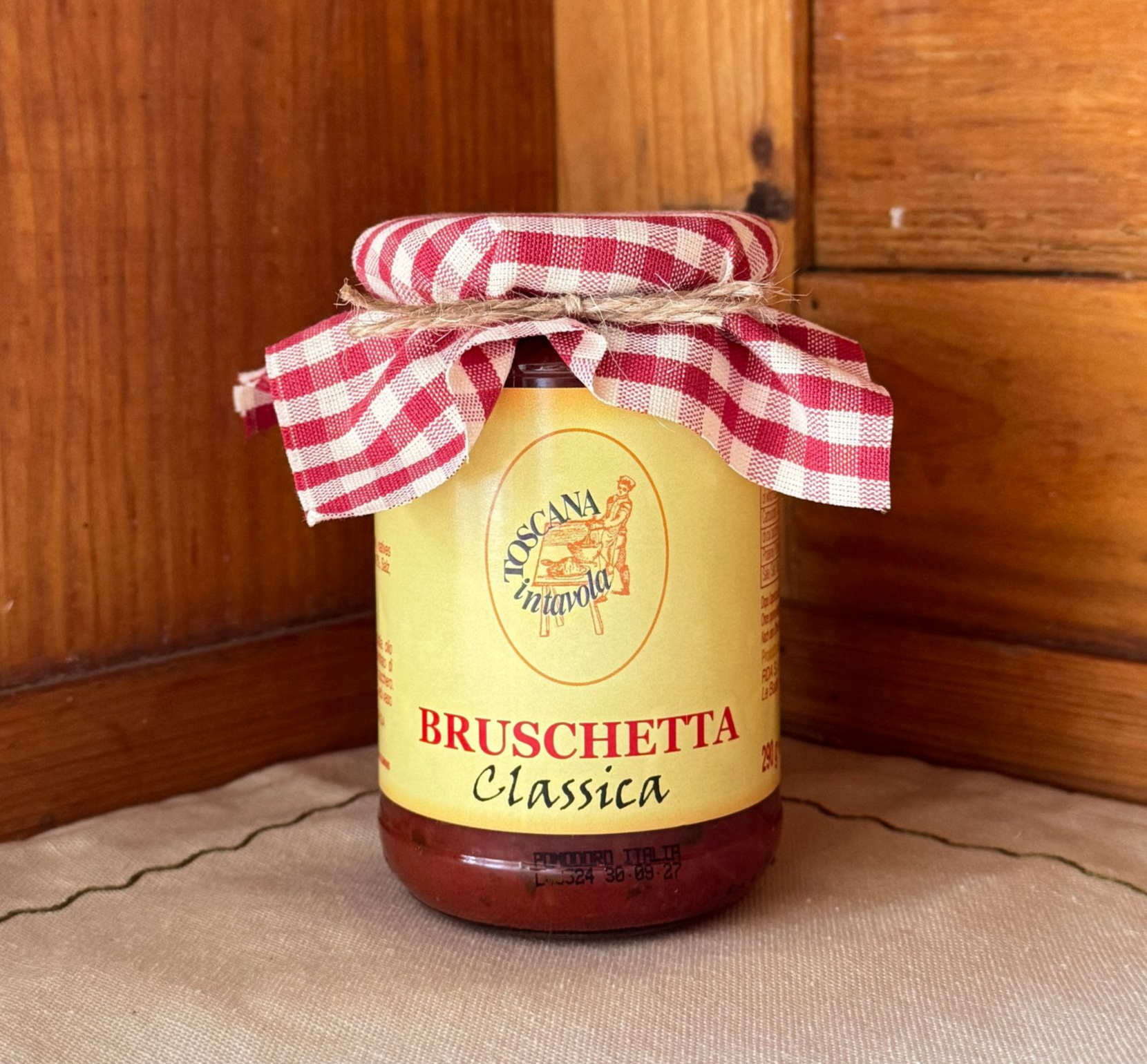 Einwegglas gefüllt mit Bruschetta Classica und mit einem durch Schnur am Deckel festgebundenem Stoff