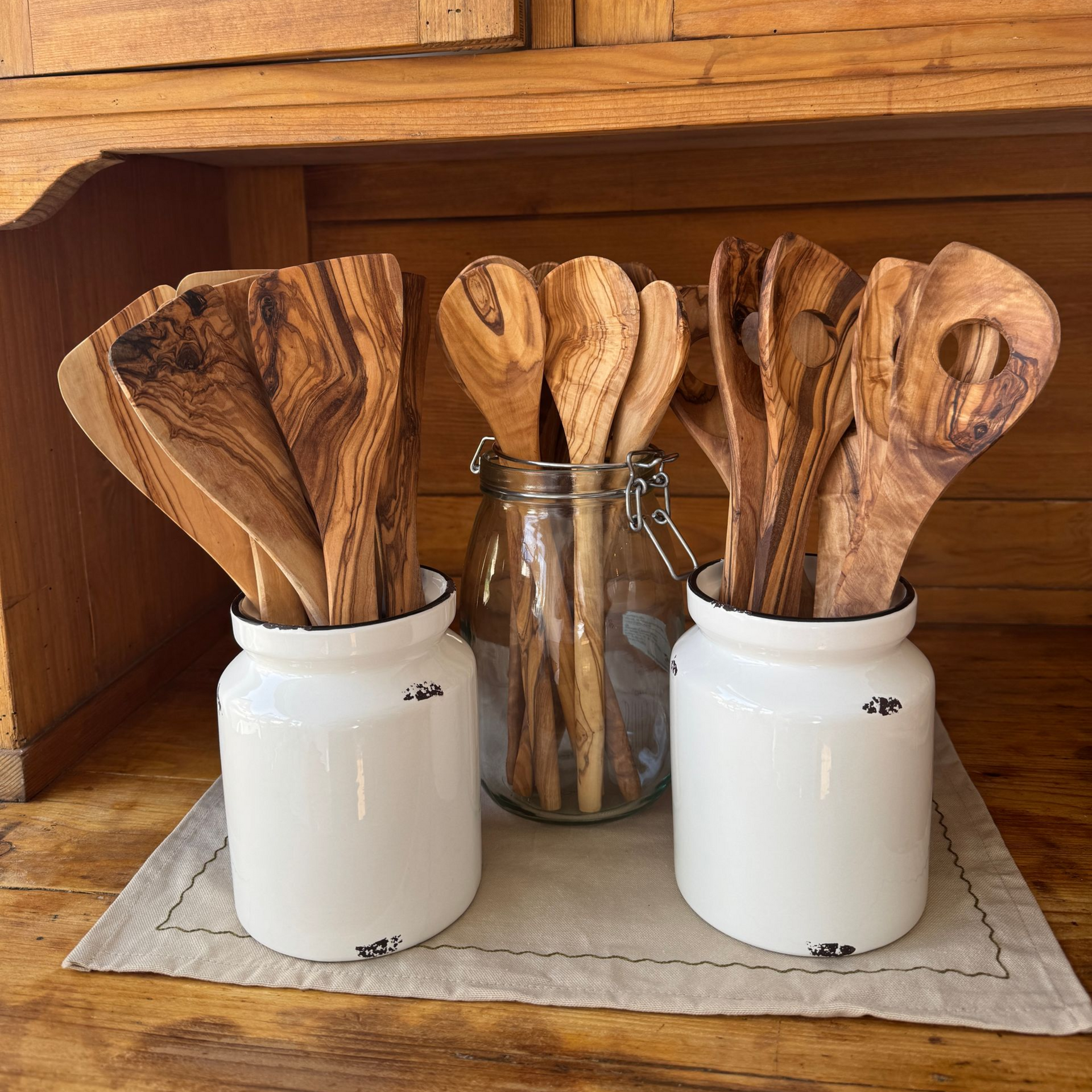 drei hohe Gefäße in denen sich Pfannenwender, Kochlöffel und Risottolöffel aus Olivenholz befinden