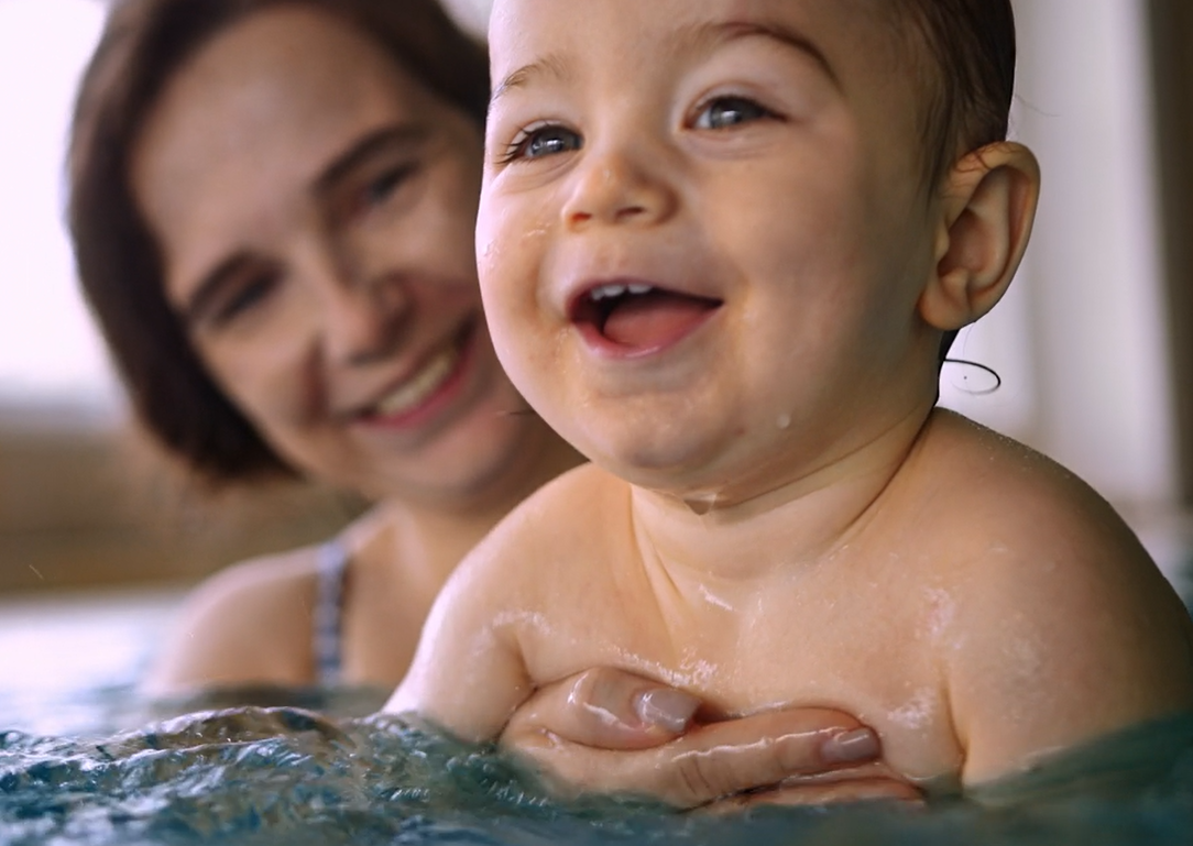 Eine Mutter hält ein lachendes Baby im Wasser