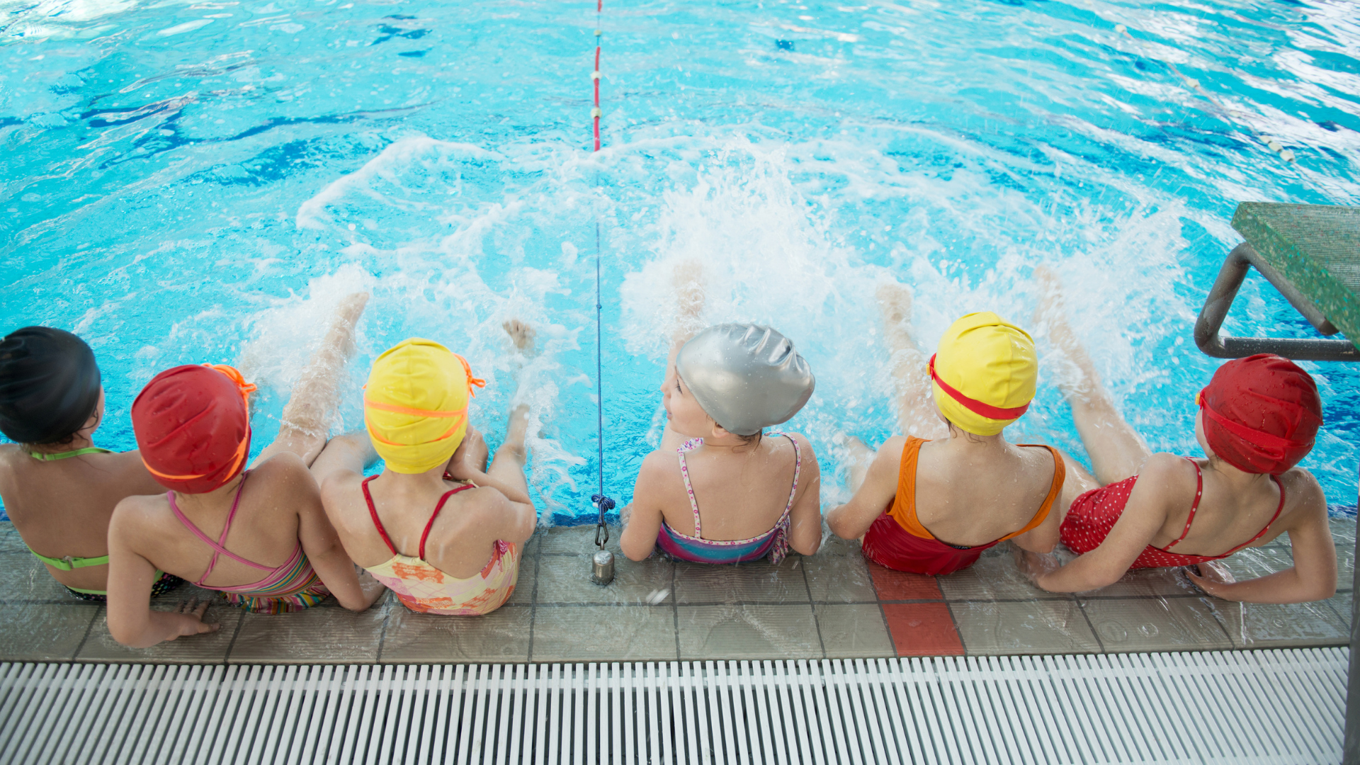 6 Kinder sitzen am Beckenrand und plantschen