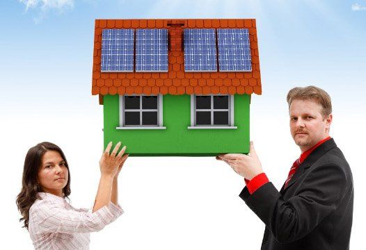 2 Menschen halten symbolisch ein Haus mit Sonnenkollektoren