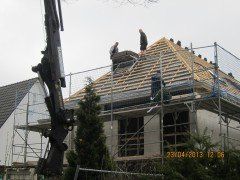 Einfamilienhaus mit Baugerüst und Arbeiter auf Dach, Bauüberwachung