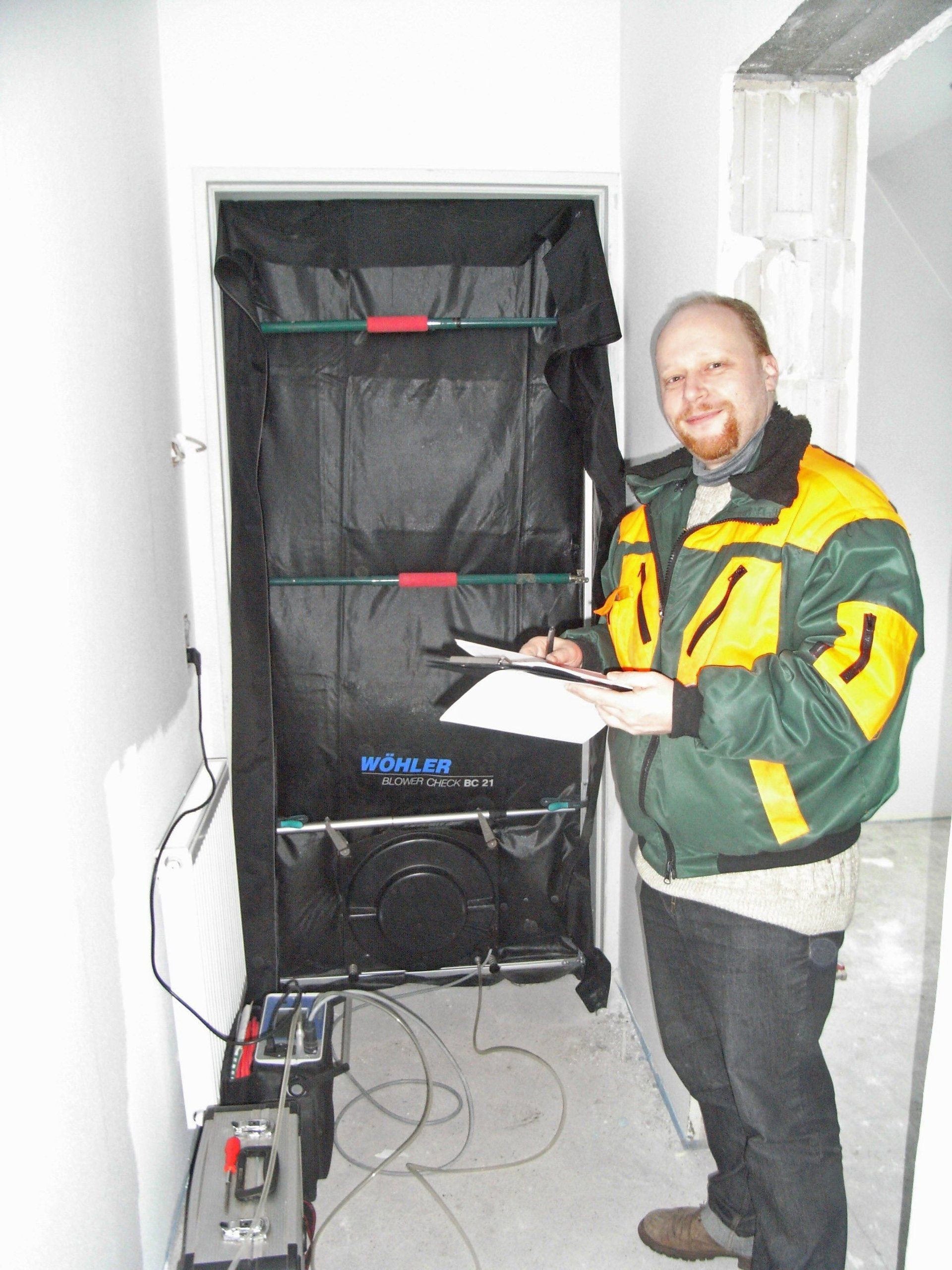 Bausachverständiger führt Blower-Door-Test mit Kleingebläse an Tür durch
