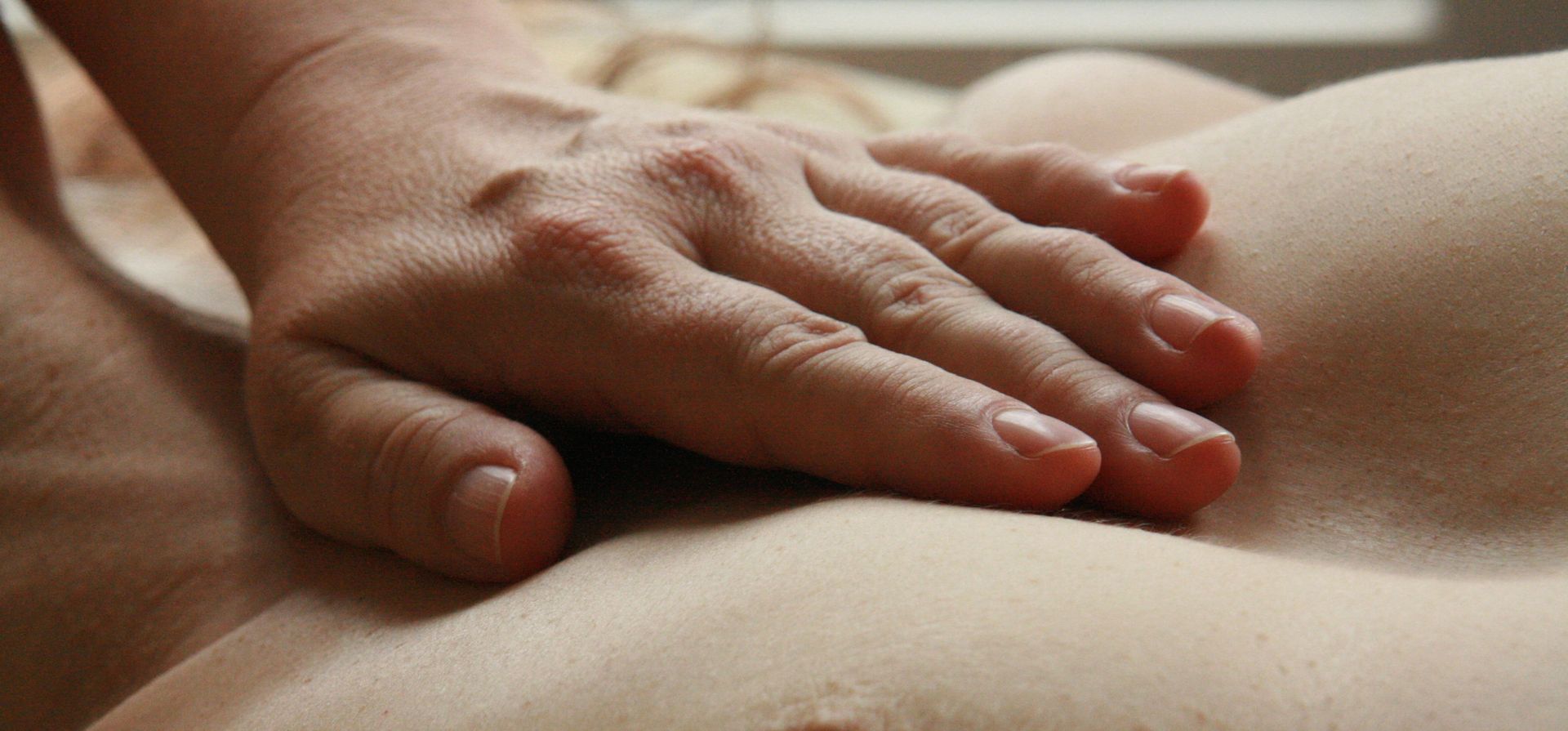 eine Hand berührt liebevoll den Brustkorb einer nackten Person als Symbol für Sinnlichkeit abseits der Genitalien