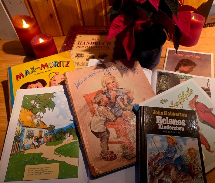 Auf einem Tisch mit Kerzen und einer Blume liegen verschiedene Bücher, die ein veraltetes Rollenbild transportieren: 