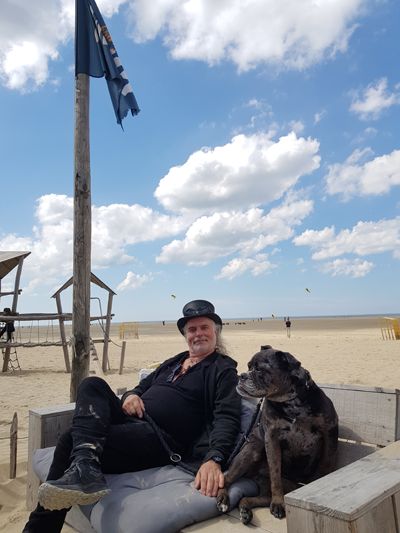 Mann und Hund sitzen am Strand auf einem Lounge-Sitz