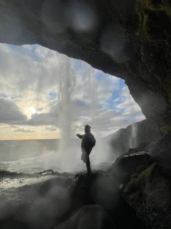 Blick aus einer Höhle hinter einem Wasserfall, Silouette eines Mannes am Wasser