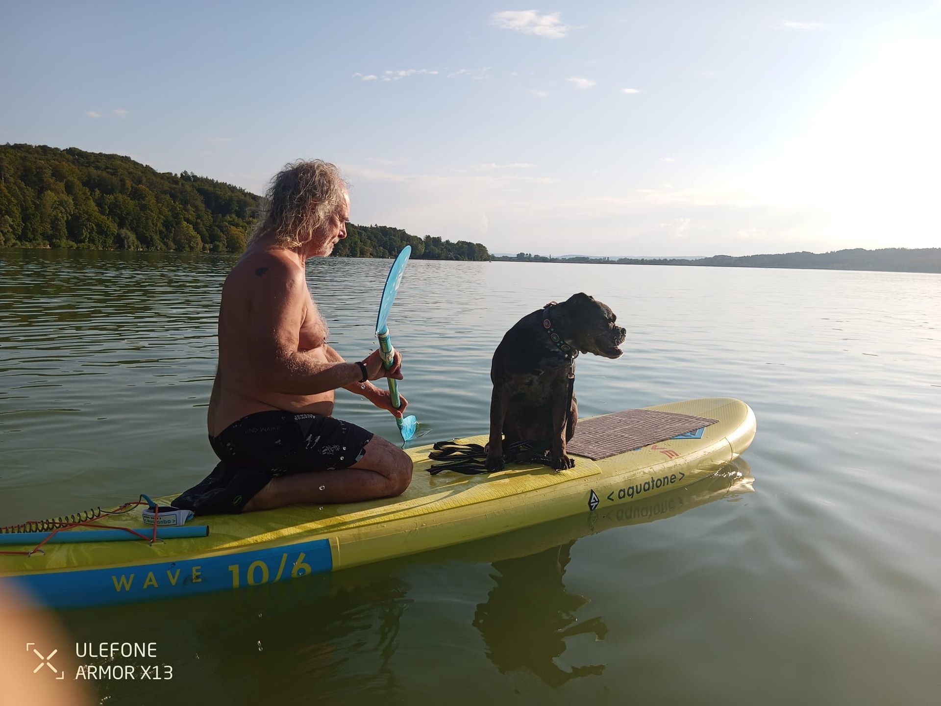 Thomas und Hund sitzen auf einem gelben SUP und paddeln auf dem Pilsensee