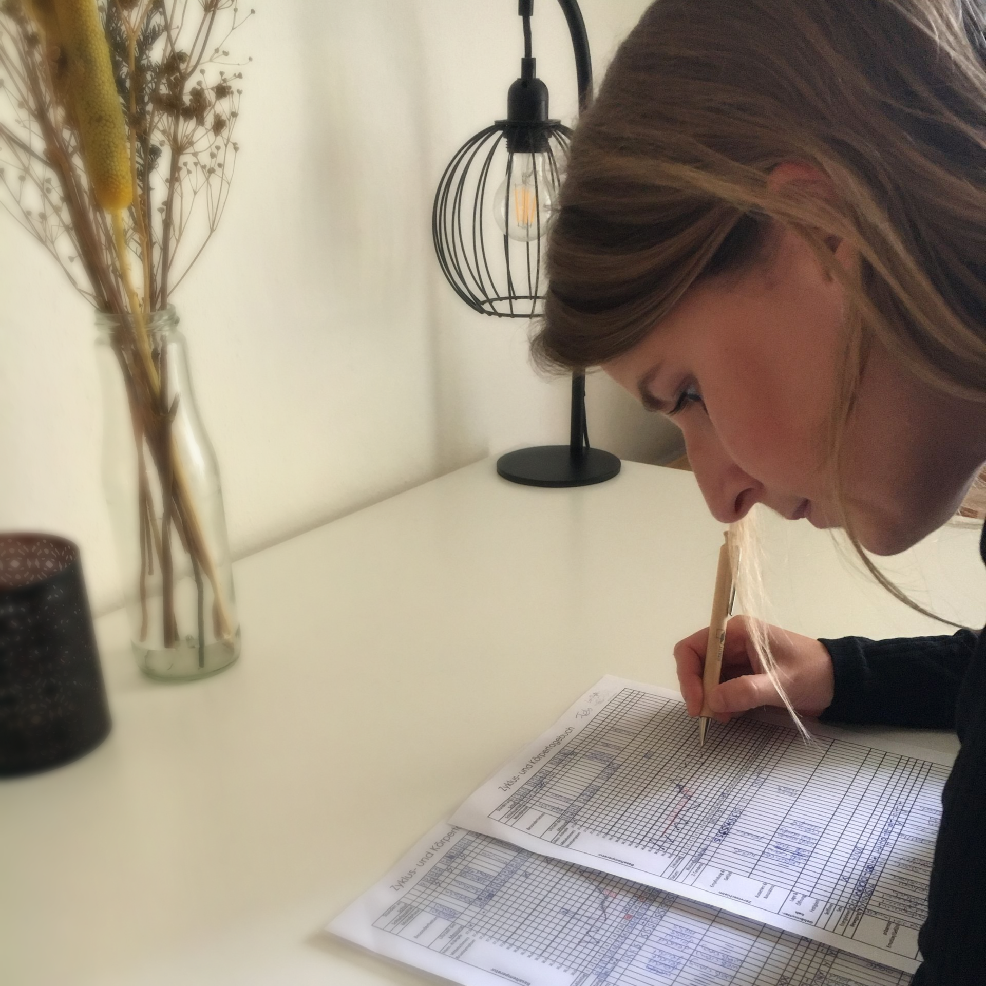 Frau über eine Zeichnung gebeugt, mit einem Stift in der Hand. Sie analysiert die Abbildung. 