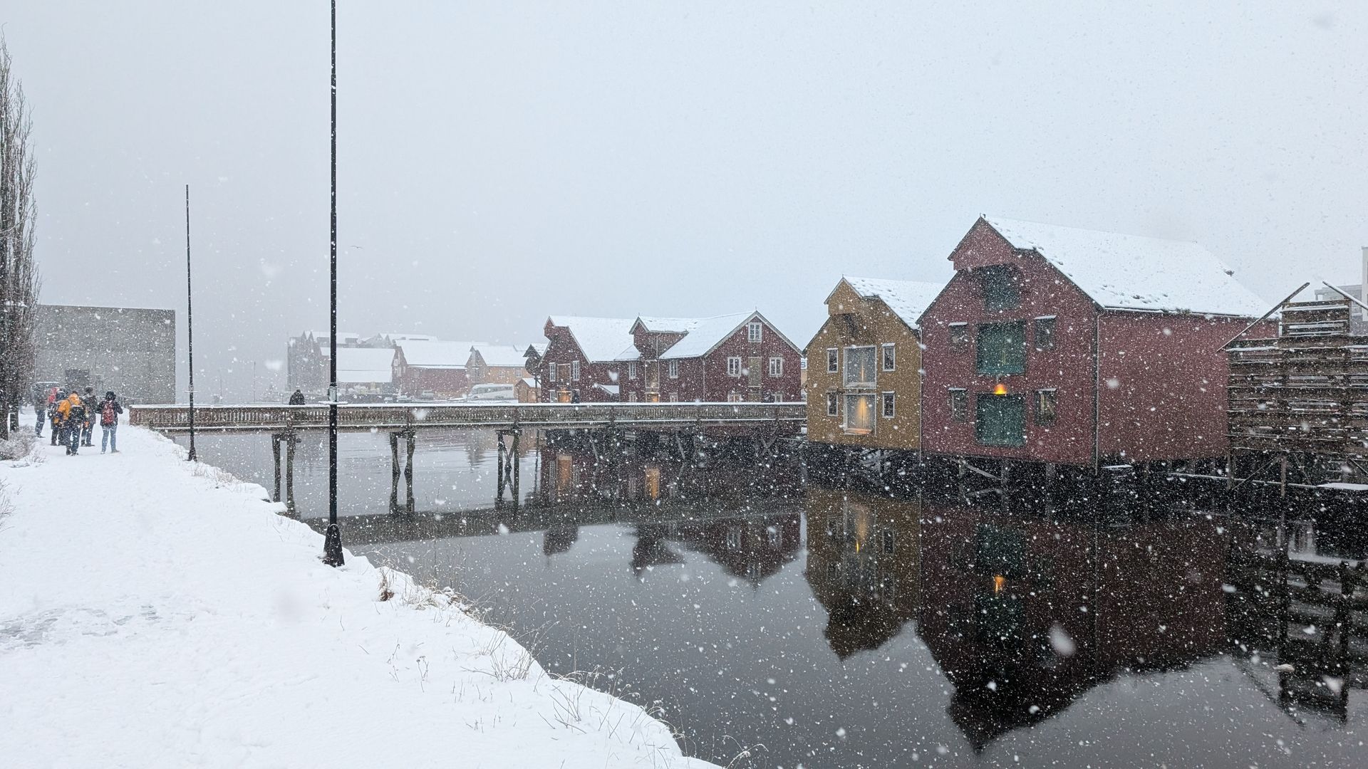 Verschneite Szene mit farbenfrohen Holzhäusern entlang eines Flusses in Trondheim, Norwegen.